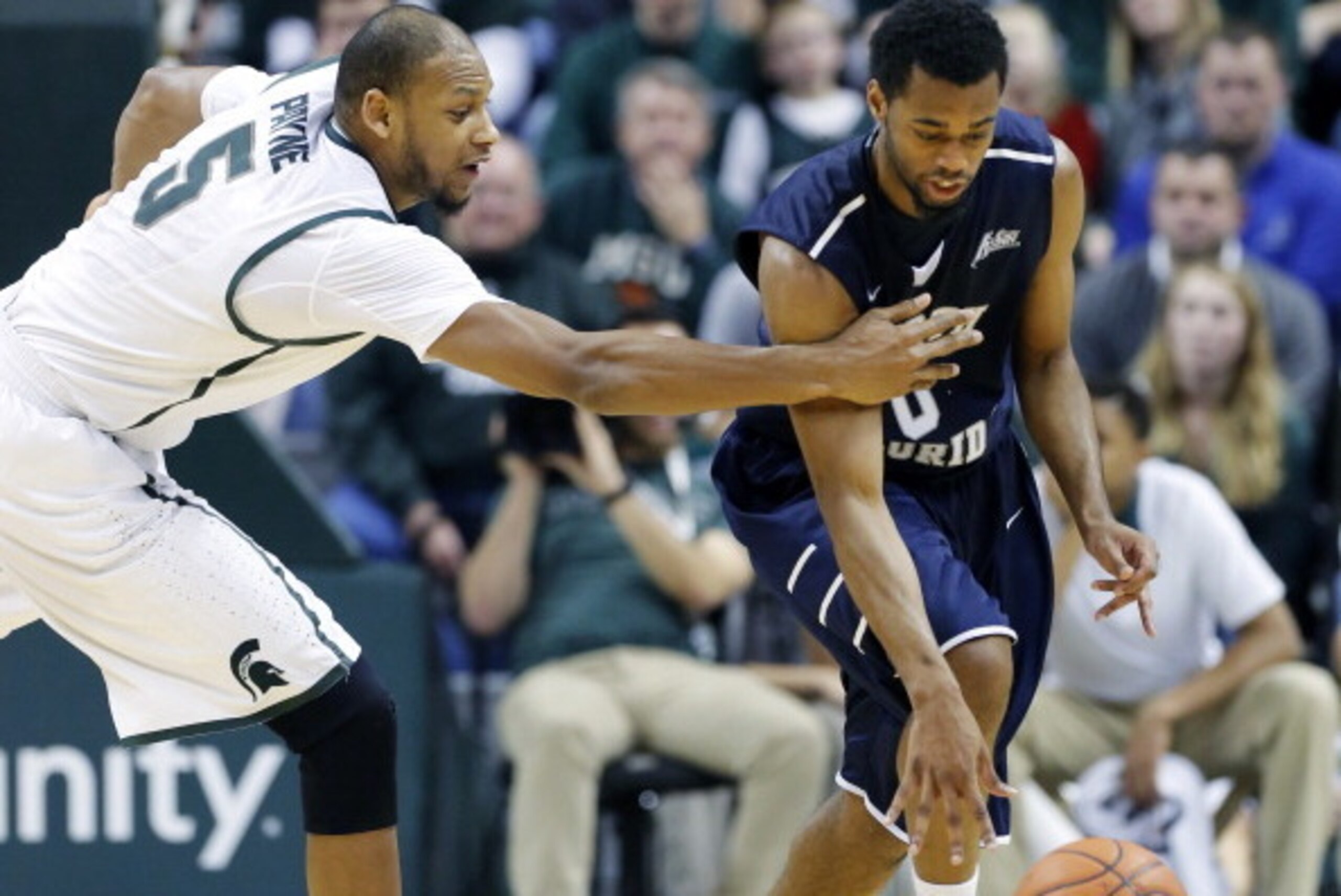 EAST LANSING, MI - DECEMBER 17:  Jalen Nesbitt #0 of the North Florida Ospreys is fouled by Adreian Payne #5 of the Michigan State Spartans during the second half of a game at Breslin Center on December 17, 2013, in East Lansing, Michigan. (Photo by Duane