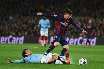 BARCELONA, SPAIN - MARCH 18:  David Silva of Manchester City tackles Lionel Messi of Barcelona during the UEFA Champions League Round of 16 second leg match between Barcelona and Manchester City at Camp Nou on March 18, 2015 in Barcelona, Spain.  (Photo b