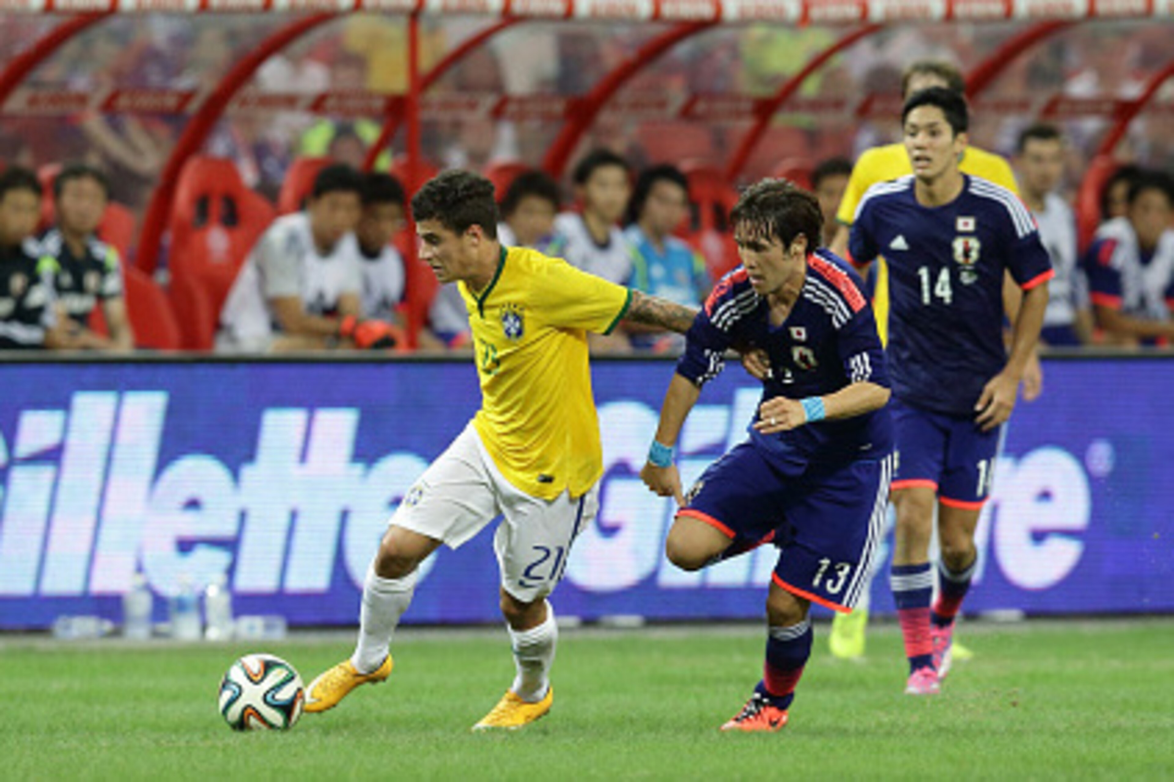 SINGAPORE - OCTOBER 14: Philippe Coutinho of Brazil (L) fends off the challenge from Hajime Hosogai of Japan during the international friendly match between Japan and Brazil at the National Stadium on October 14, 2014 in Singapore.  (Photo by Suhaimi Abdu