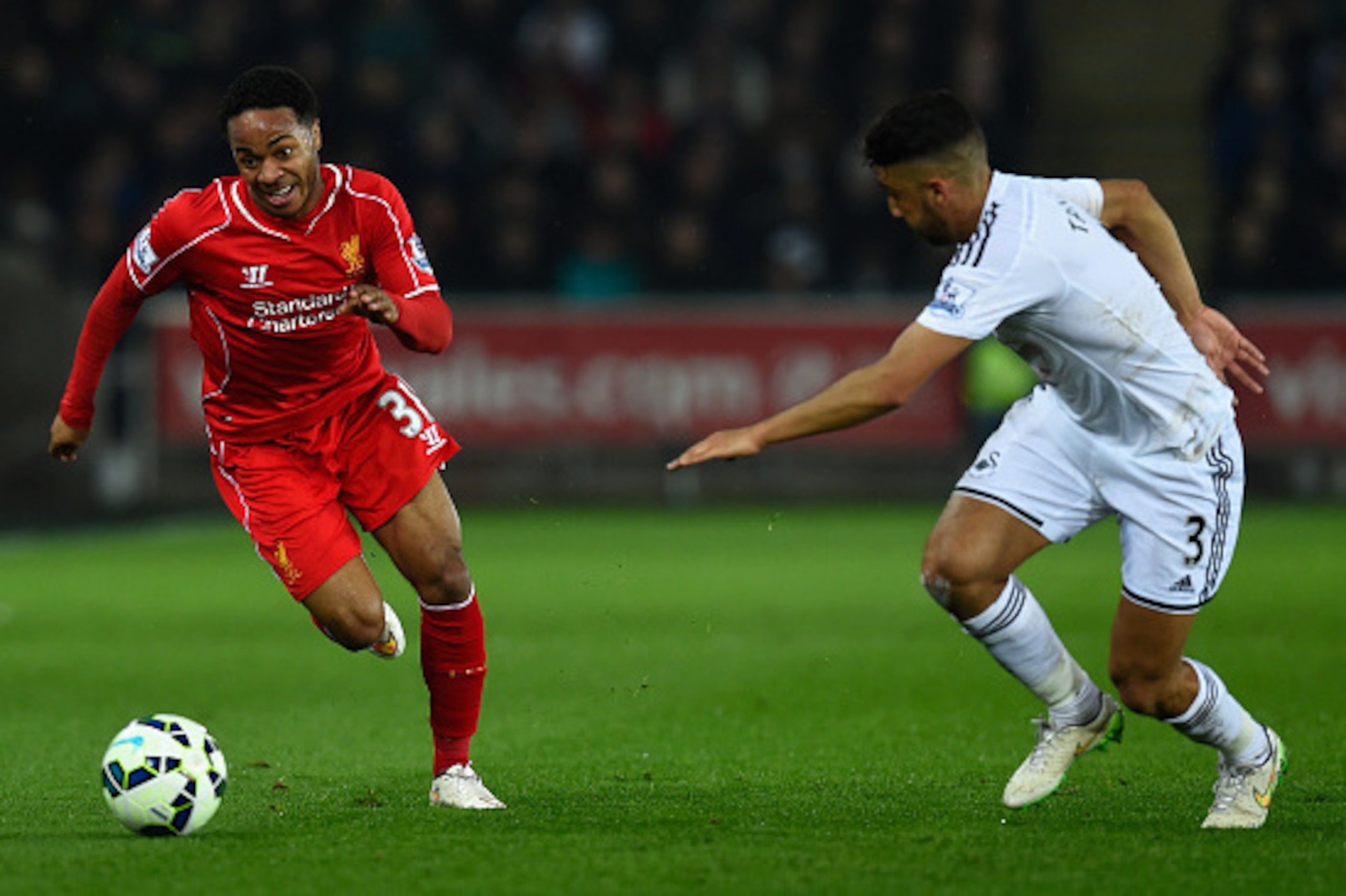 SWANSEA, WALES - MARCH 16:  Liverpool player Raheem Sterling (l) takes on Neil Taylor of Swansea during the Barclays Premiership match between Swansea City and Liverpool at Liberty Stadium on March 16, 2015 in Swansea, Wales.  (Photo by Stu Forster/Getty 