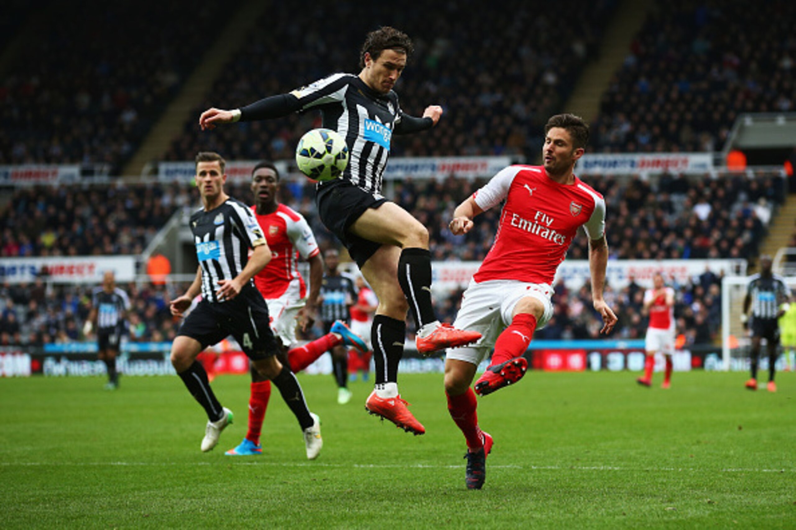 NEWCASTLE UPON TYNE, ENGLAND - MARCH 21: Olivier Giroud of Arsenal is challenged by Daryl Janmaat of Newcastle United during the Barclays Premier League match between Newcastle United and Arsenal at St James' Park on March 21, 2015 in Newcastle upon Tyne,