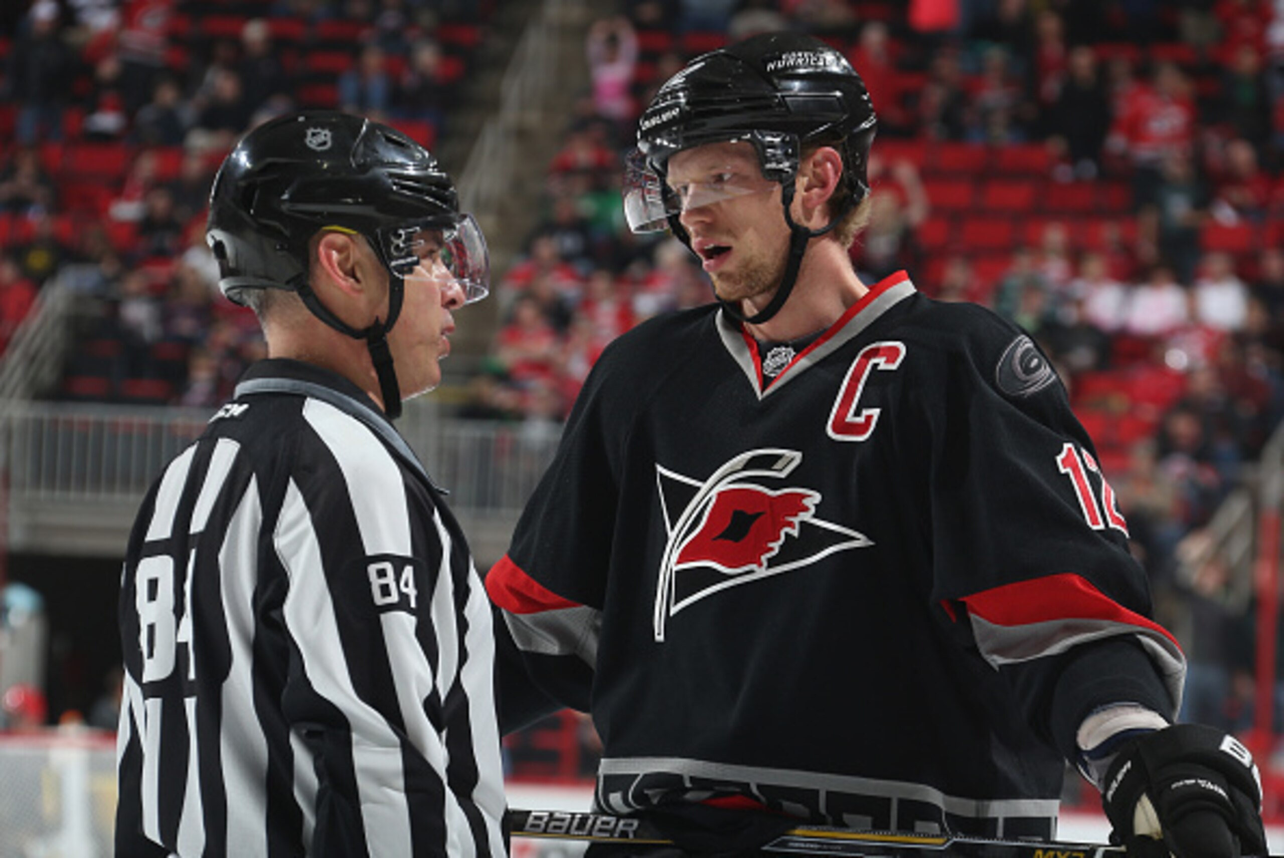 RALEIGH, NC - MARCH 14: Eric Staal #12 of the Carolina Hurricanes has a conversation during a timeout with linesman Tony Siricolo #84 during their NHL game against the Florida Panthers at PNC Arena on March 14, 2015 in Raleigh, North Carolina.  (Photo by 