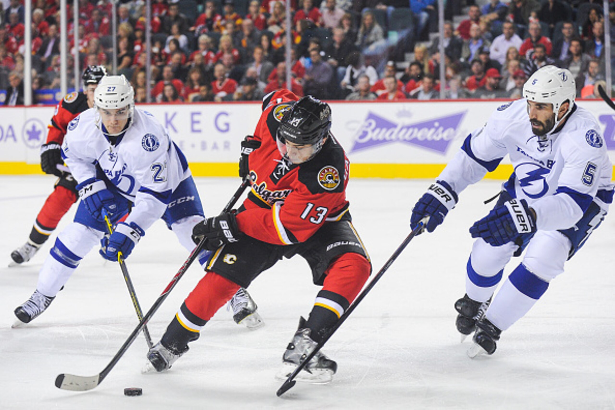 CALGARY, AB - OCTOBER 21: Johnny Gaudreau #13 of the Calgary Flames carries the puck as Jonathan Drouin #27 (L) and Jason Garrison #5 (R) of the Tampa Bay Lightning try to check him during an NHL game at Scotiabank Saddledome on October 21, 2014 in Calgar CALGARY, AB - OCTOBER 21: Johnny Gaudreau #13 of the Calgary Flames carries the puck as Jonathan Drouin #27 (L) and Jason Garrison #5 (R) of the Tampa Bay Lightning try to check him during an NHL game at Scotiabank Saddledome on October 21, 2014 in Calgar