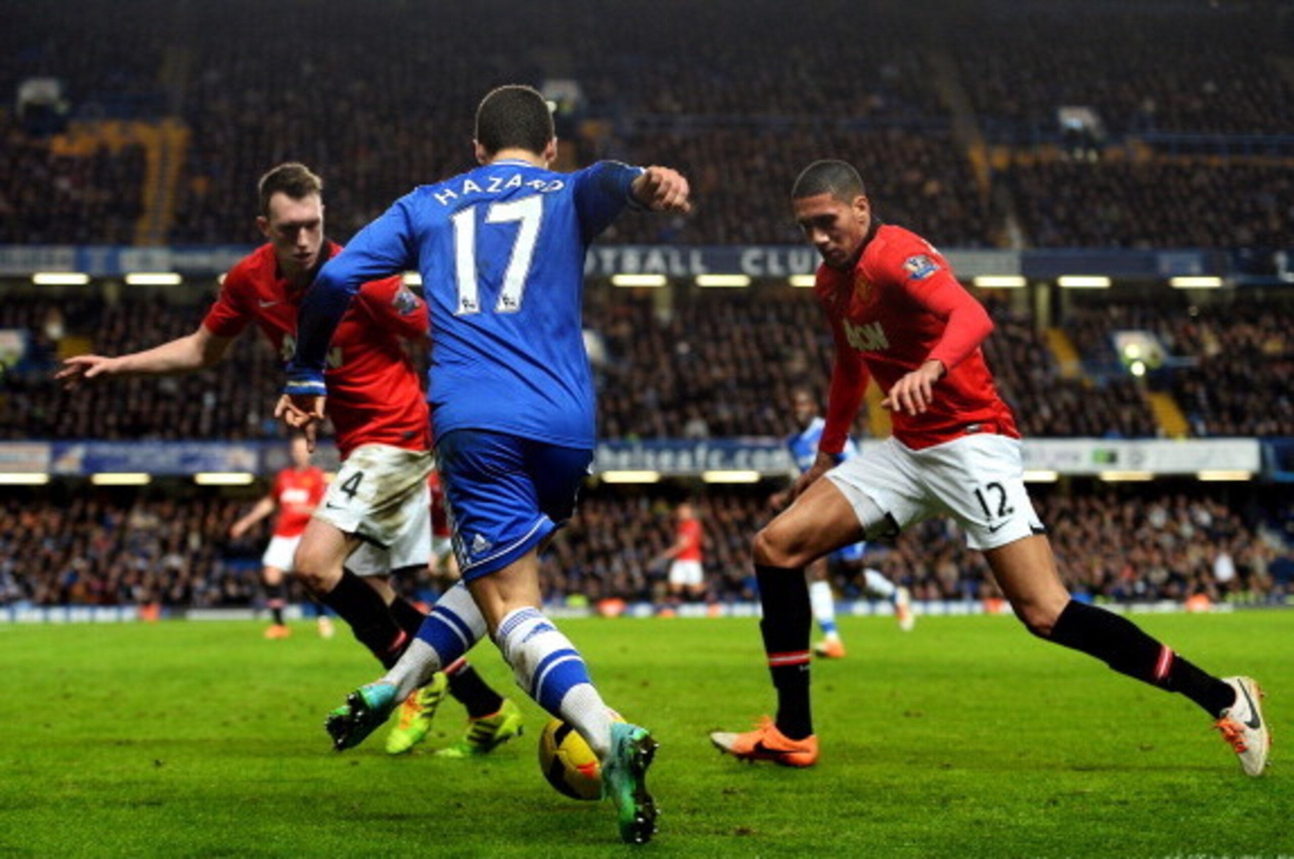 LONDON, ENGLAND - JANUARY 19:  Eden Hazard of Chelsea is challenged by Phil Jones (L) and Chris Smalling (R) of Manchester United during the Barclays Premier League match between Chelsea and Manchester United at Stamford Bridge on January 19, 2014 in Lond