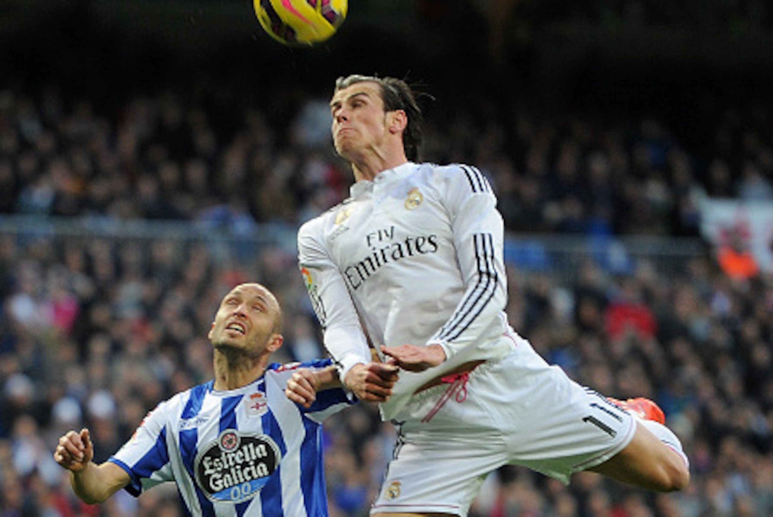 MADRID, SPAIN - FEBRUARY 15:  Gareth Bale of Real Madrid heads the ball beside  Laureano Sanabria ''Laure'' of RC Deportivo La Coruna during the La Liga match between Real Madrid CF and RC Deportivo La Coruna at Estadio Santiago Bernabeu on February 15, 2