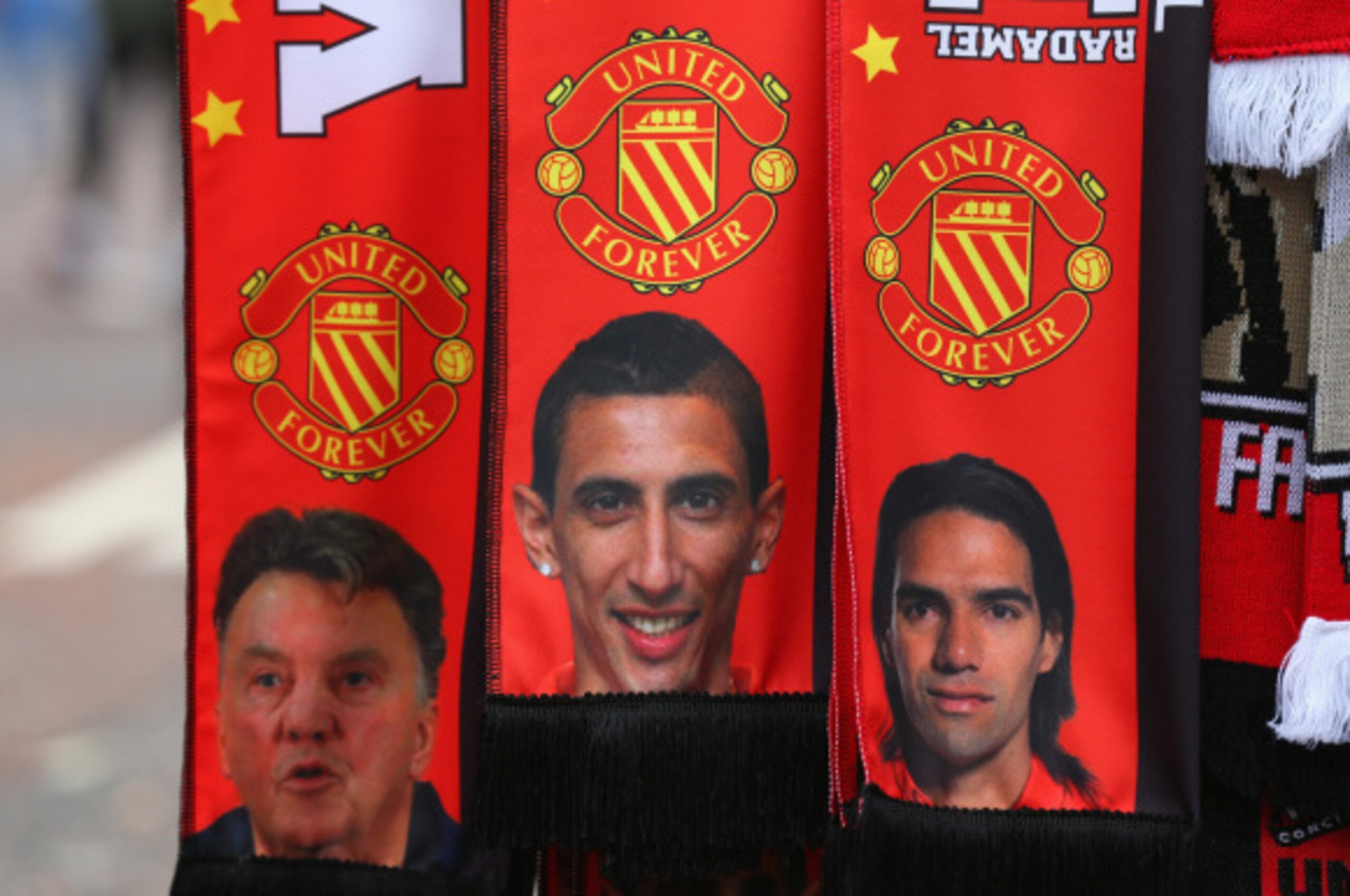 MANCHESTER, ENGLAND - SEPTEMBER 14:  A vendor sells scarves showing  Manager Louis van Gaal and new signings Falcao and Angel Di Maria prior to the Barclays Premier League match between Manchester United and Queens Park Rangers at Old Trafford on Septembe