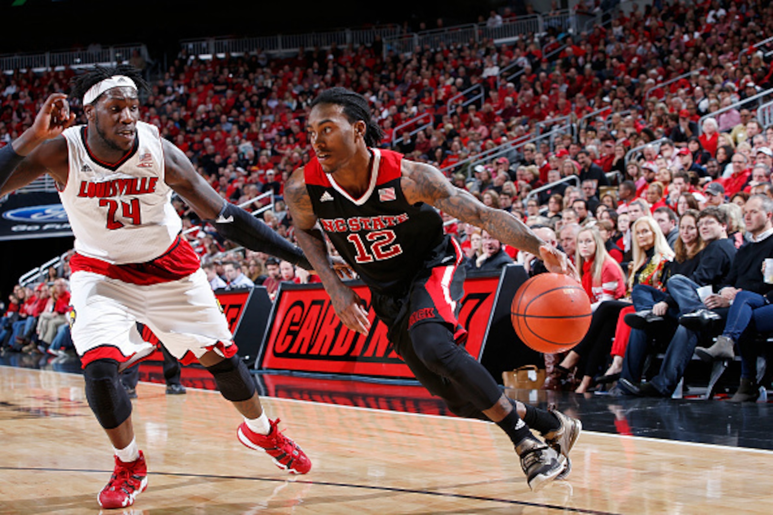 LOUISVILLE, KY - FEBRUARY 14: Anthony Barber #12 of the North Carolina State Wolfpack drives to the basket against Montrezl Harrell #24 of the Louisville Cardinals during the game at KFC Yum! Center on February 14, 2015 in Louisville, Kentucky. North Caro