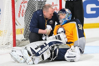 BUFFALO, NY - MARCH 26: Goaltender Matt Hackett #31 of the Buffalo Sabres receives attention from athletic trainer Tim Macre during the third period of their game against the Arizona Coyotes on March 26, 2015 at the First Niagara Center in Buffalo, New Yo