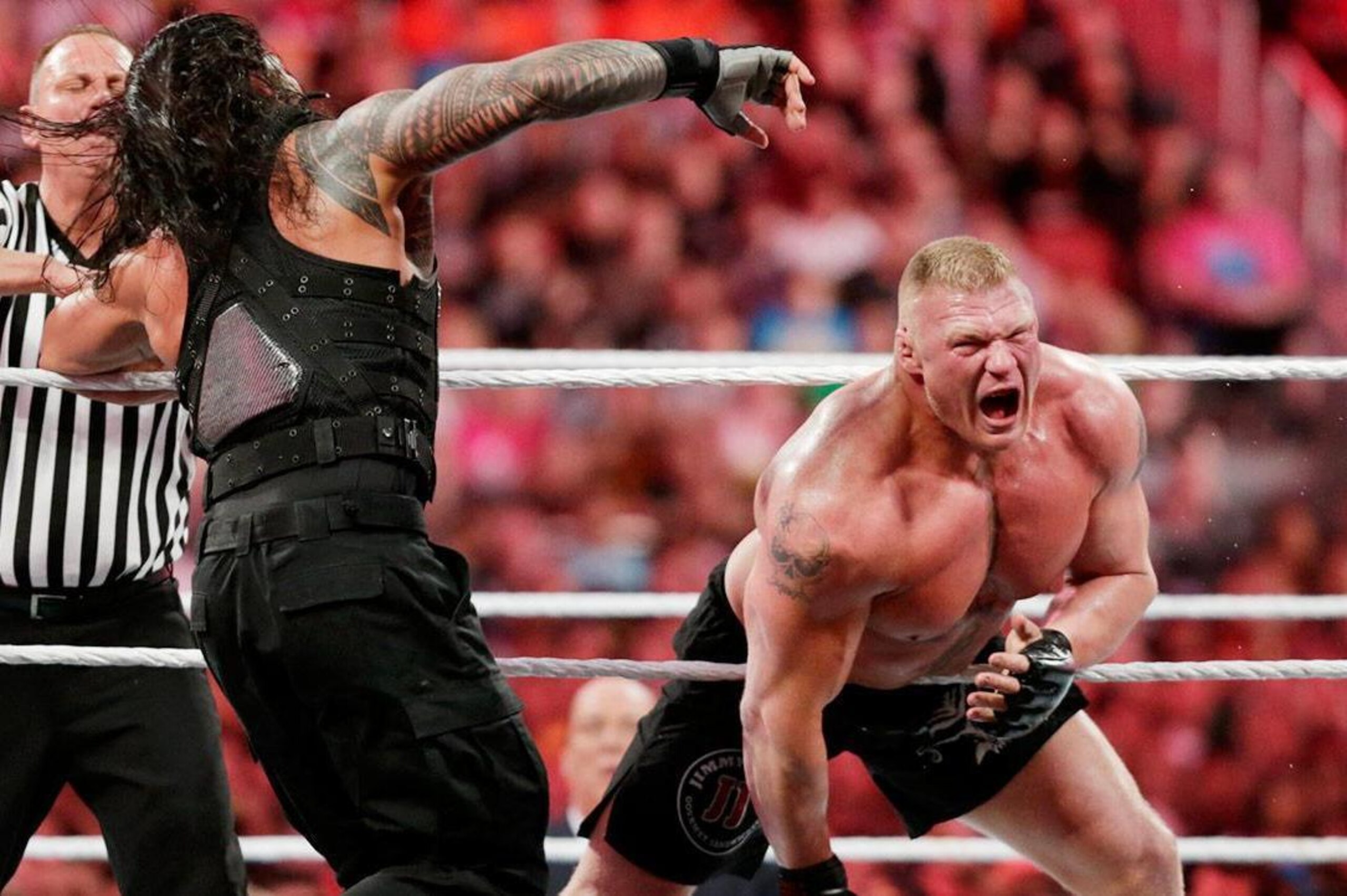 Brock Lesnar knocks Roman Reigns off the ring apron.