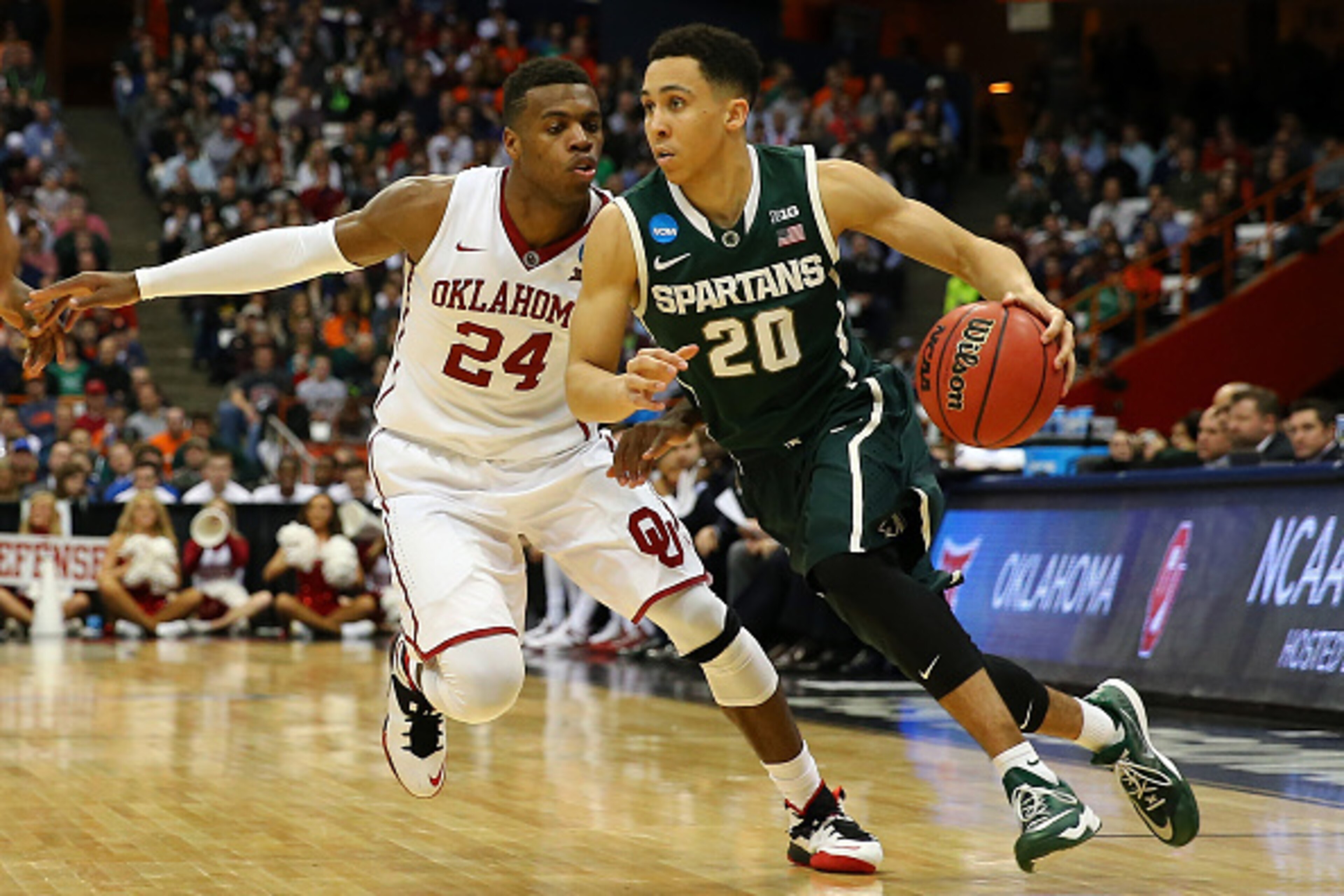 SYRACUSE, NY - MARCH 27: Travis Trice #20 of the Michigan State Spartans drives against Buddy Hield #24 of the Oklahoma Sooners during the East Regional Semifinal of the 2015 NCAA Men's Basketball Tournament at the Carrier Dome on March 27, 2015 in Syracu