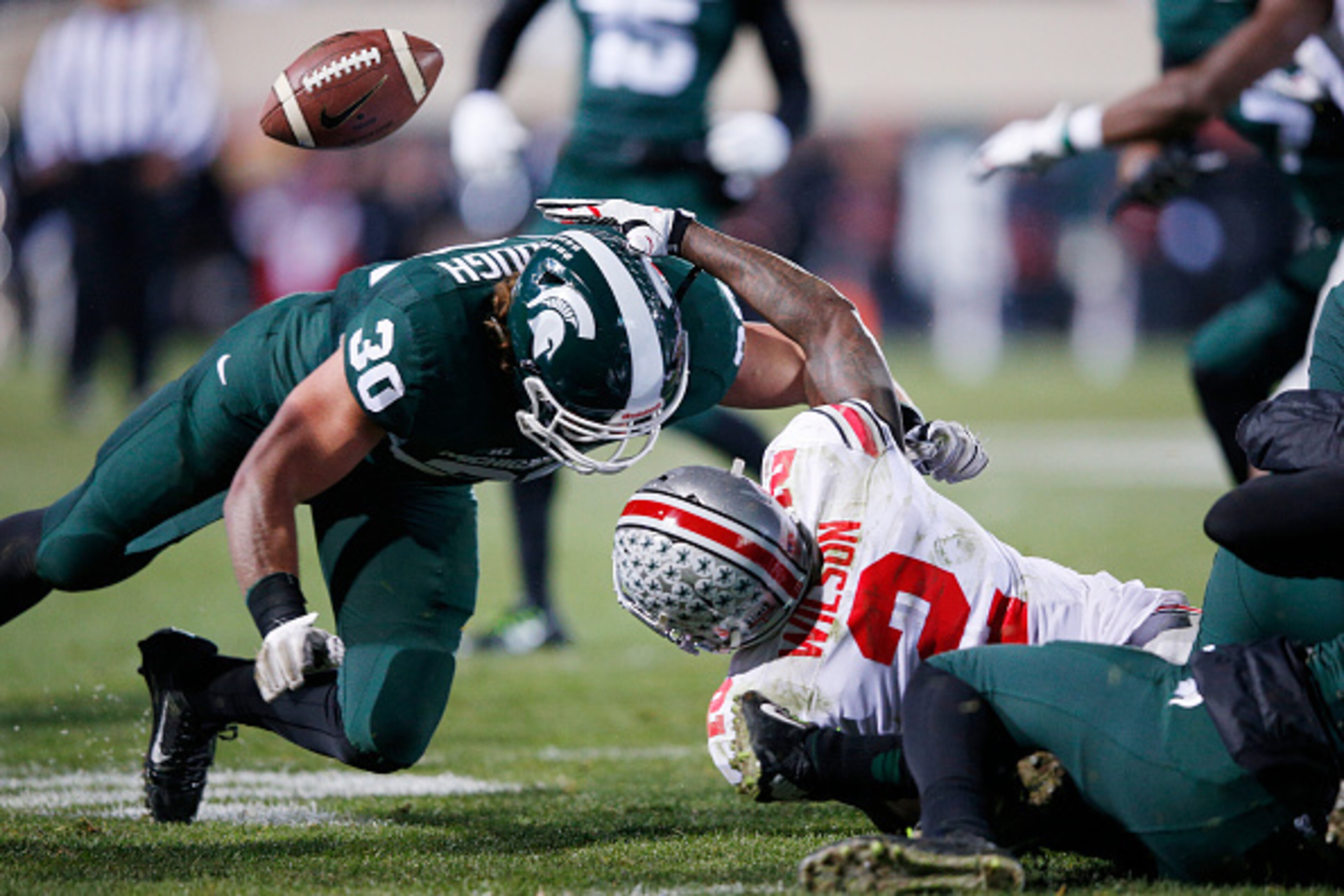 EAST LANSING, MI - NOVEMBER 8: Dontre Wilson #2 of the Ohio State Buckeyes fumbles the ball on a kick return after being hit by Riley Bullough #30 of the Michigan State Spartans in the first half of the game at Spartan Stadium on November 8, 2014 in East 