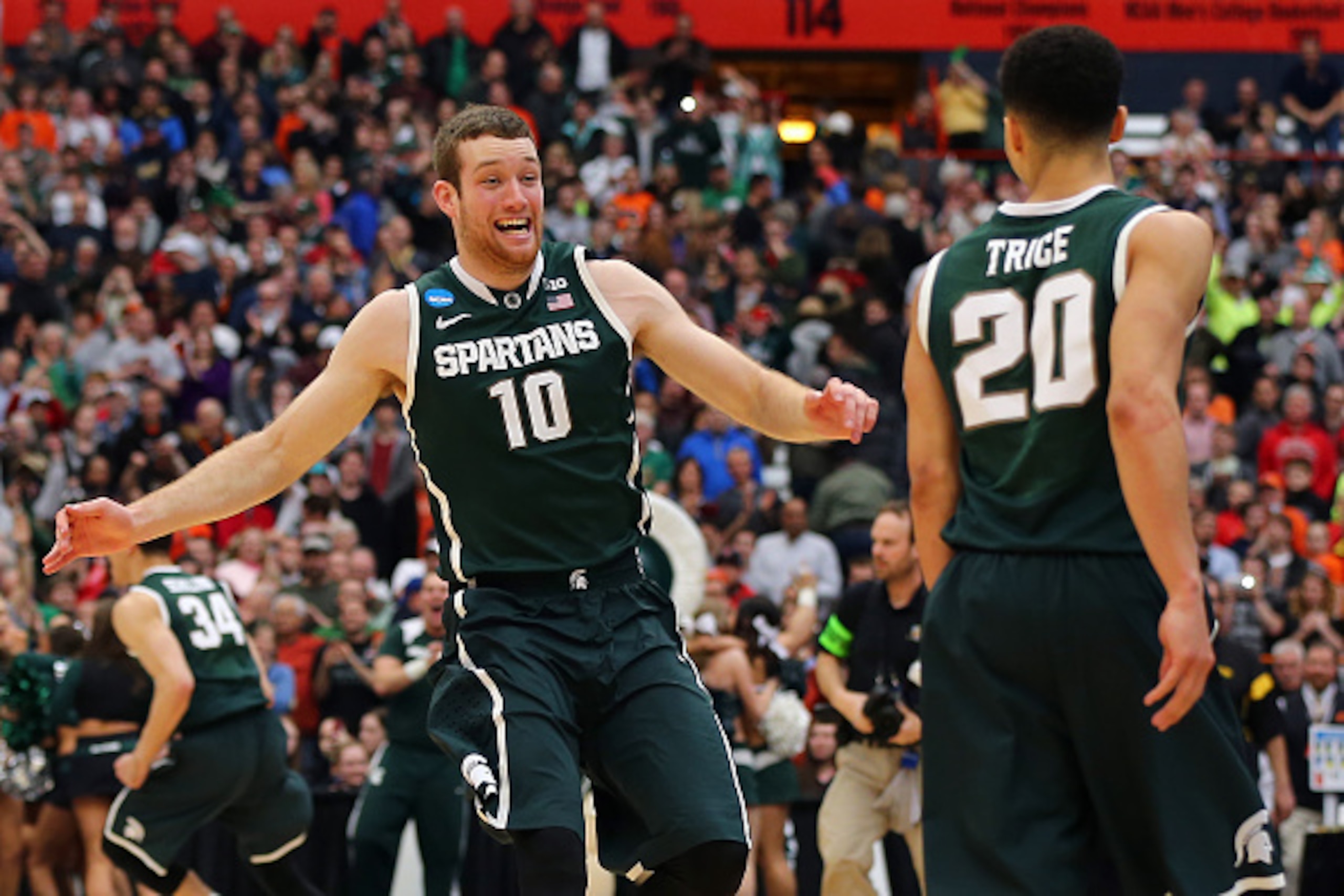 SYRACUSE, NY - MARCH 29:  Matt Costello #10 and Travis Trice #20 of the Michigan State Spartans celebrate defeating the Louisville Cardinals 76 to 70 in overtime of the East Regional Final of the 2015 NCAA Men's Basketball Tournament at Carrier Dome on Ma