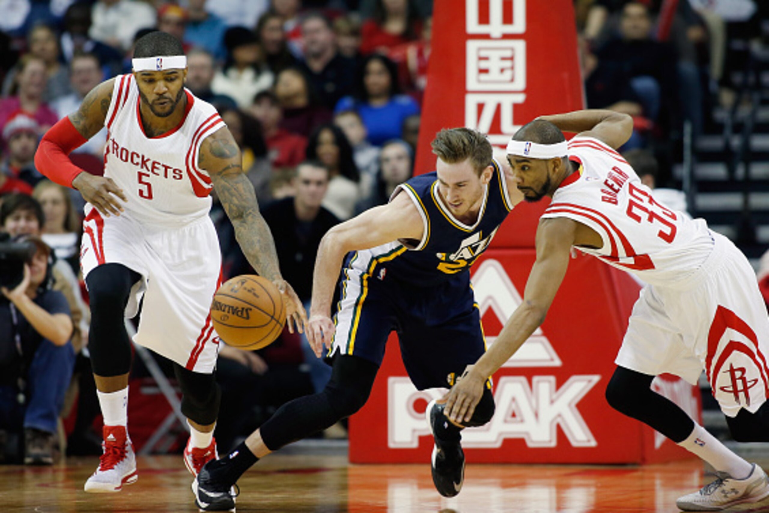 HOUSTON, TX - JANUARY 10:  Gordon Hayward #20 of the Utah Jazz reaches for the basketball in front of Josh Smith and Corey Brewer #33 of the Houston Rockets during their game at the Toyota Center on January 10, 2015 in Houston, Texas.  NOTE TO USER: User 