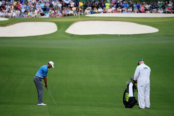 AUGUSTA, GA - APRIL 06:  Tiger Woods of the United States hits an approach shot as caddie Joe LaCava looks on during a practice round prior to the start of the 2015 Masters Tournament at Augusta National Golf Club on April 6, 2015 in Augusta, Georgia.  (P