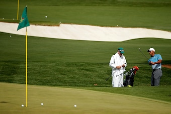 AUGUSTA, GA - APRIL 06:  Tiger Woods (R) of the United States hits a chip shot on the practice range as caddie Joe LaCava (L) looks on during a practice round prior to the start of the 2015 Masters Tournament at Augusta National Golf Club on April 6, 2015