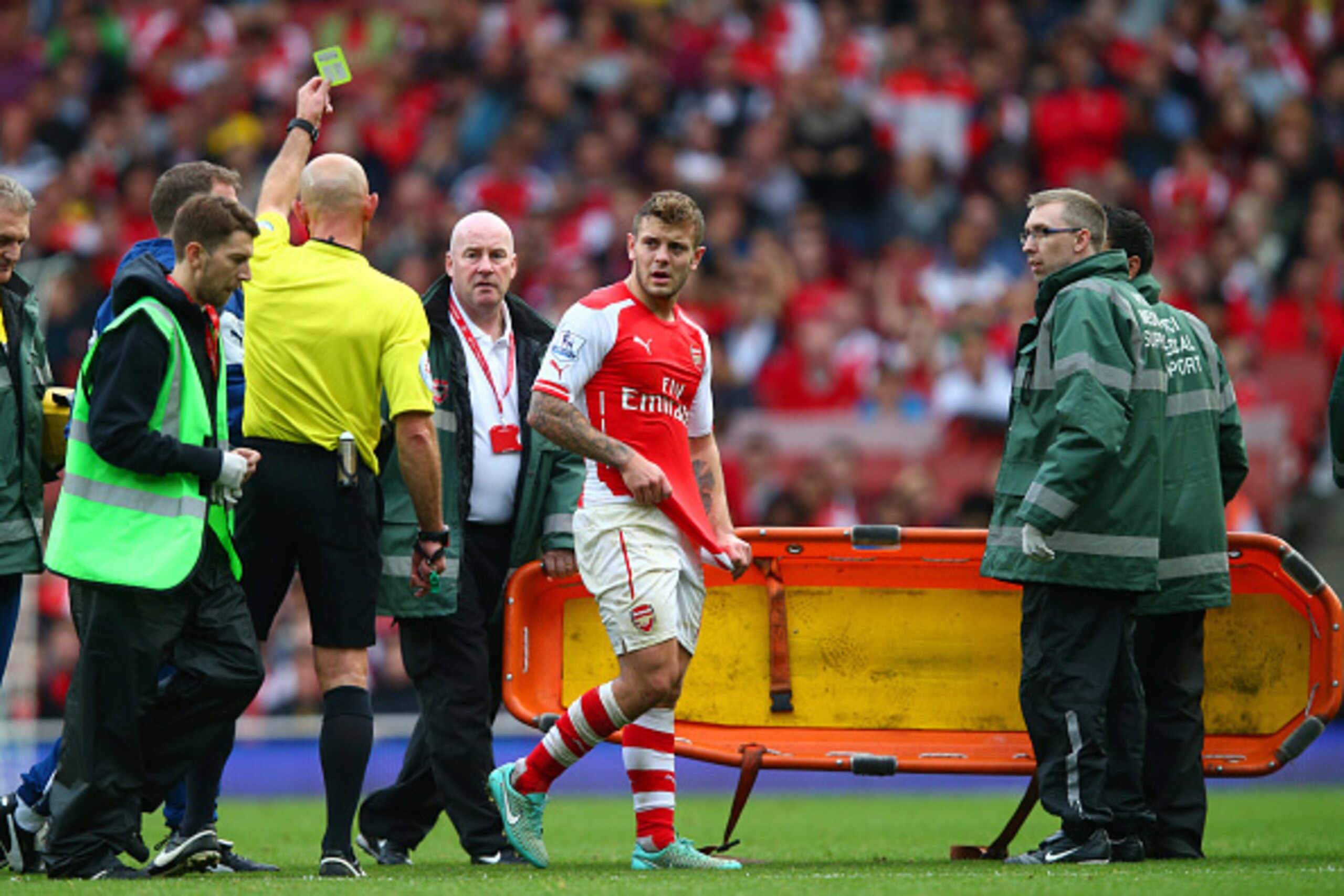 LONDON, ENGLAND - OCTOBER 18:  Jack Wilshere of Arsenal receives a yellow card from referee Roger East as he leaves the field with an injury during the Barclays Premier League match between Arsenal and Hull City at Emirates Stadium on October 18, 2014 in 