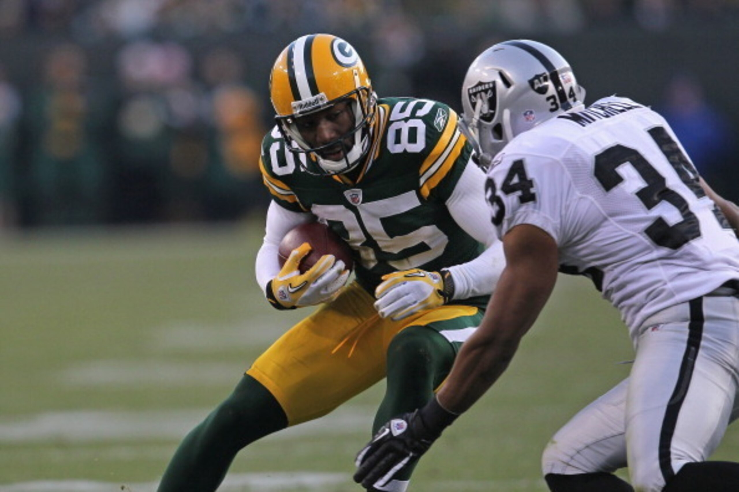 GREEN BAY, WI - DECEMBER 11: Greg Jennings #85 of the Green Bay Packers makes a move on Mike Mitchell #34 of the Oakland Raiders at Lambeau Field on December 11, 2011 in Green Bay, Wisconsin. The Packers defeated the Raiders 46-16. (Photo by Jonathan Dani