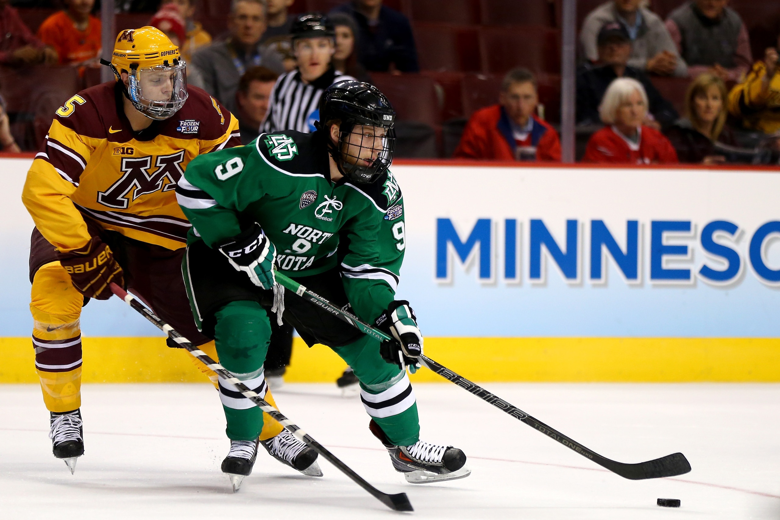 PHILADELPHIA, PA - APRIL 10: Drake Caggiula #9 of the North Dakota Fighting Sioux takes the puck as Mike Reilly #5 of the Minnesota Gophers defends in the first period during the 2014 NCAA Division I Men's Hockey Championship Semifinal at Wells Fargo Cen PHILADELPHIA, PA - APRIL 10: Drake Caggiula #9 of the North Dakota Fighting Sioux takes the puck as Mike Reilly #5 of the Minnesota Gophers defends in the first period during the 2014 NCAA Division I Men's Hockey Championship Semifinal at Wells Fargo Cen