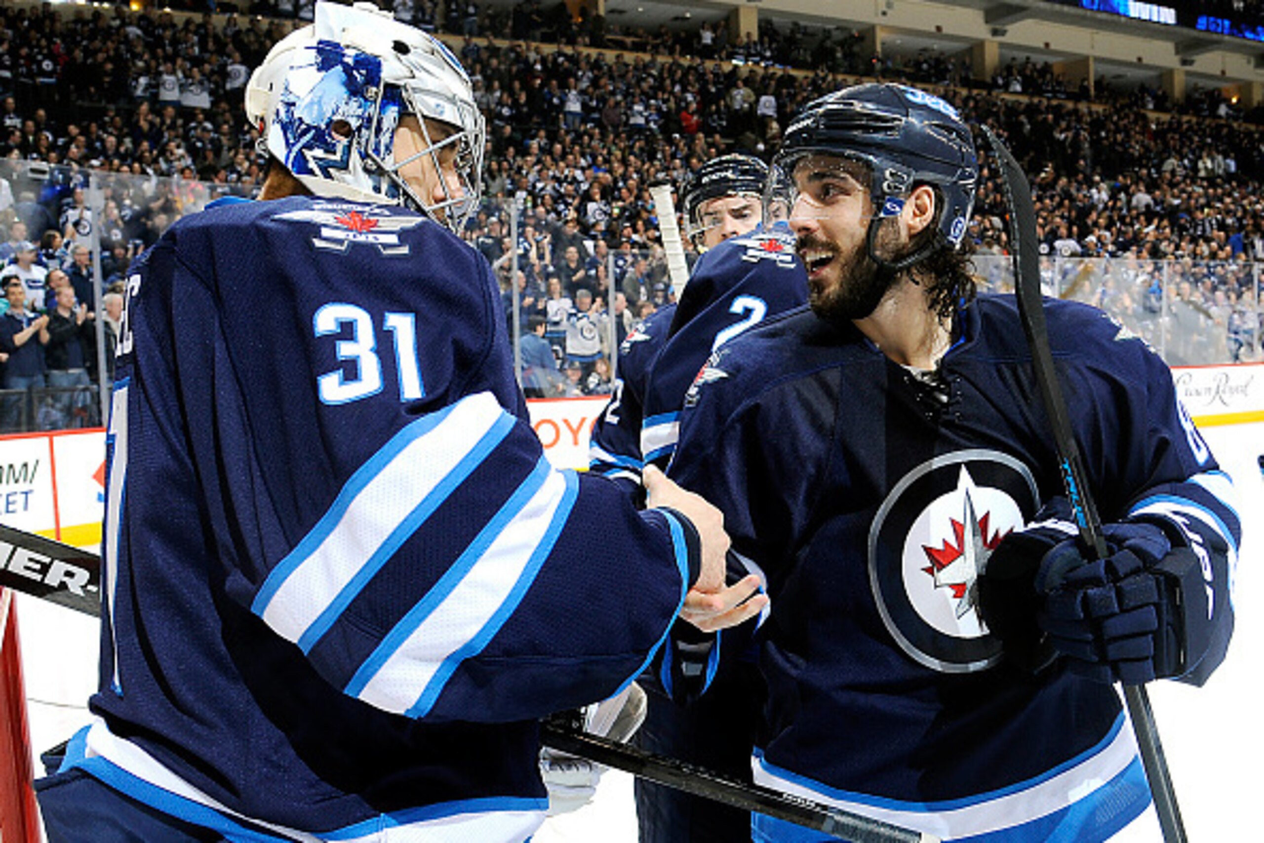 WINNIPEG, CANADA - APRIL 4: Goaltender Ondrej Pavelec #31 of the Winnipeg Jets shakes hands with teammate Mathieu Perreault #85 as they celebrate a 5-4 victory over the Vancouver Canucks on April 4, 2015 at the MTS Centre in Winnipeg, Manitoba, Canada.  (