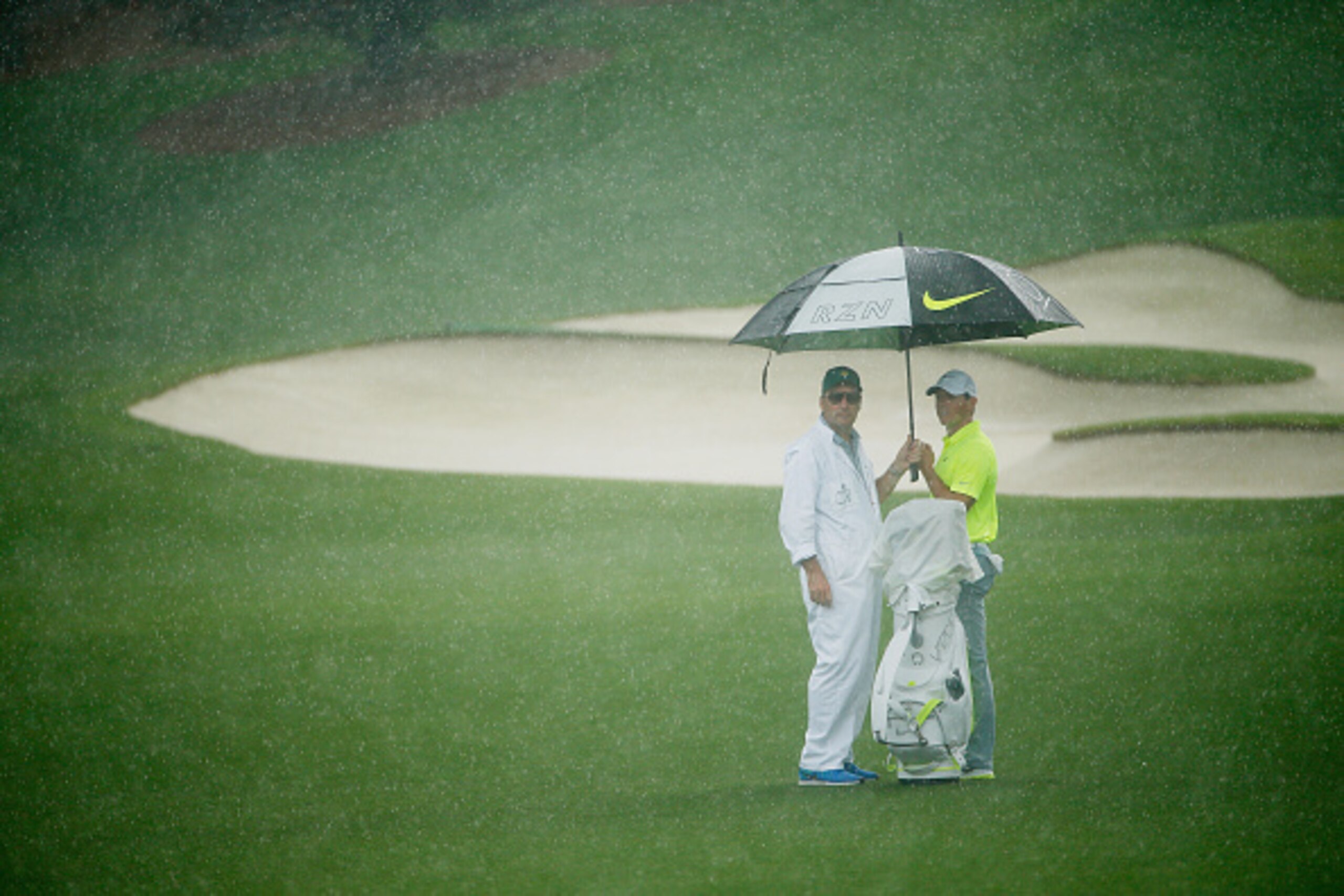 AUGUSTA, GA - APRIL 07:  Rory McIlroy of Northern Ireland waits with his caddie J.P. Fitzgerald in the rain during a practice round prior to the start of the 2015 Masters Tournament at Augusta National Golf Club on April 7, 2015 in Augusta, Georgia.  (Pho