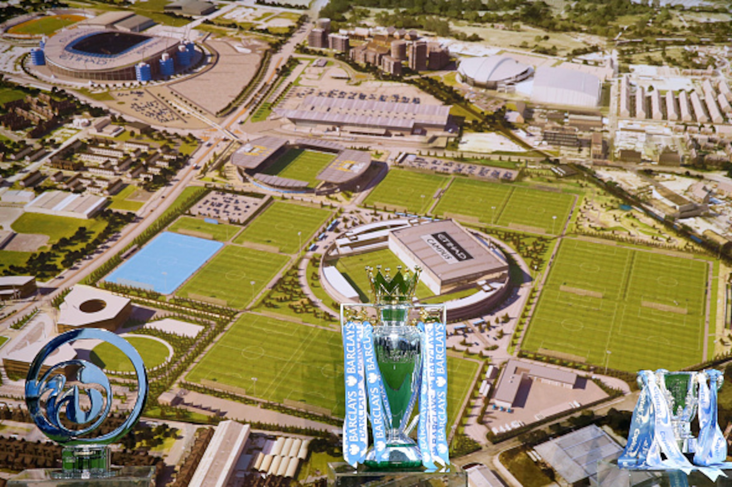 MANCHESTER, ENGLAND - DECEMBER 08:  Trophies sit in front of an aerial photograph during the official launch of the Manchester City Football Academy at the City Football Academy on December 8, 2014 in Manchester, United Kingdom.  (Photo by Alex Livesey/Ge