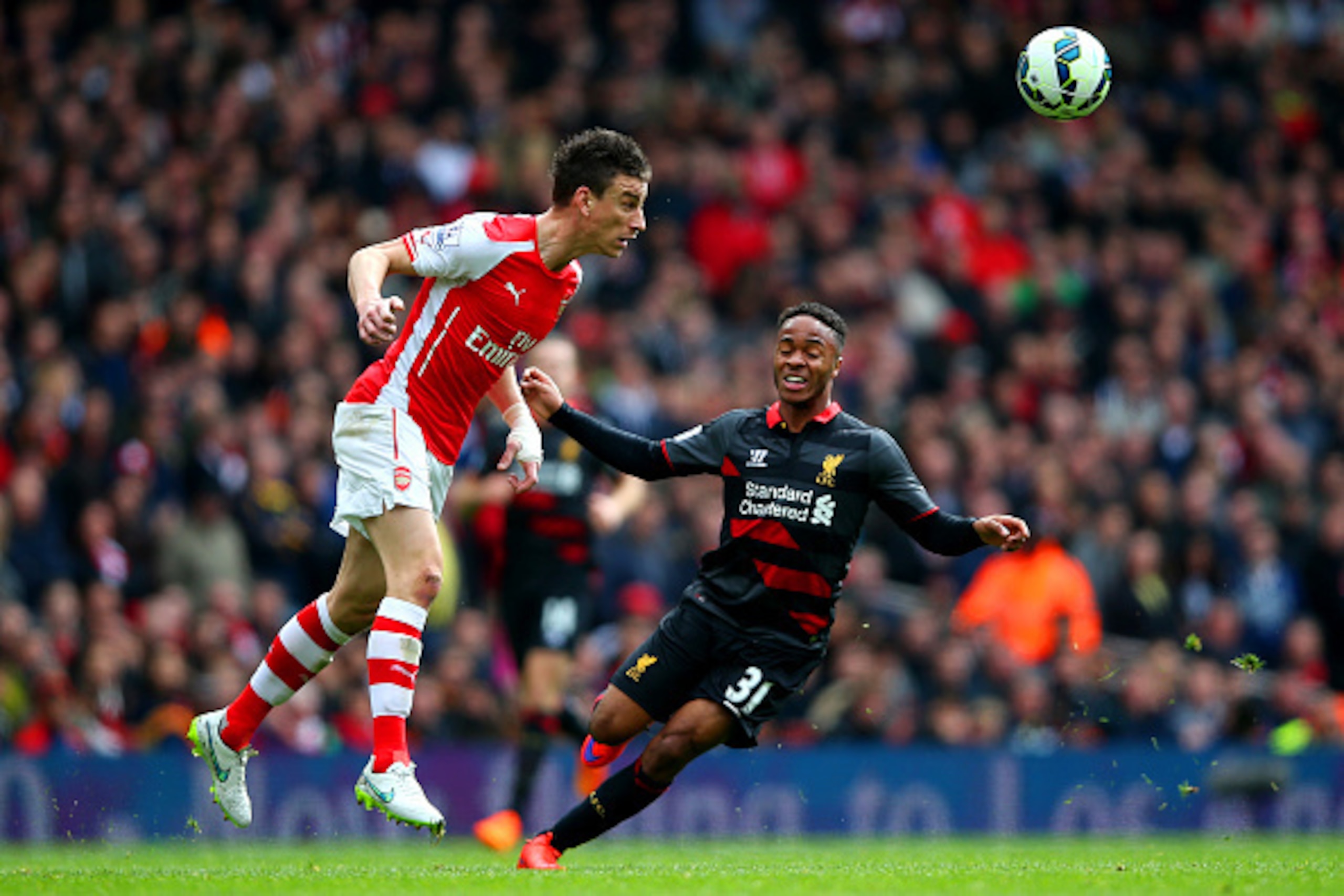 LONDON, ENGLAND - APRIL 04:  Laurent Koscielny of Arsenal clears the ball under pressure from Raheem Sterling of Liverpool during the Barclays Premier League match between Arsenal and Liverpool at Emirates Stadium on April 4, 2015 in London, England.  (Ph