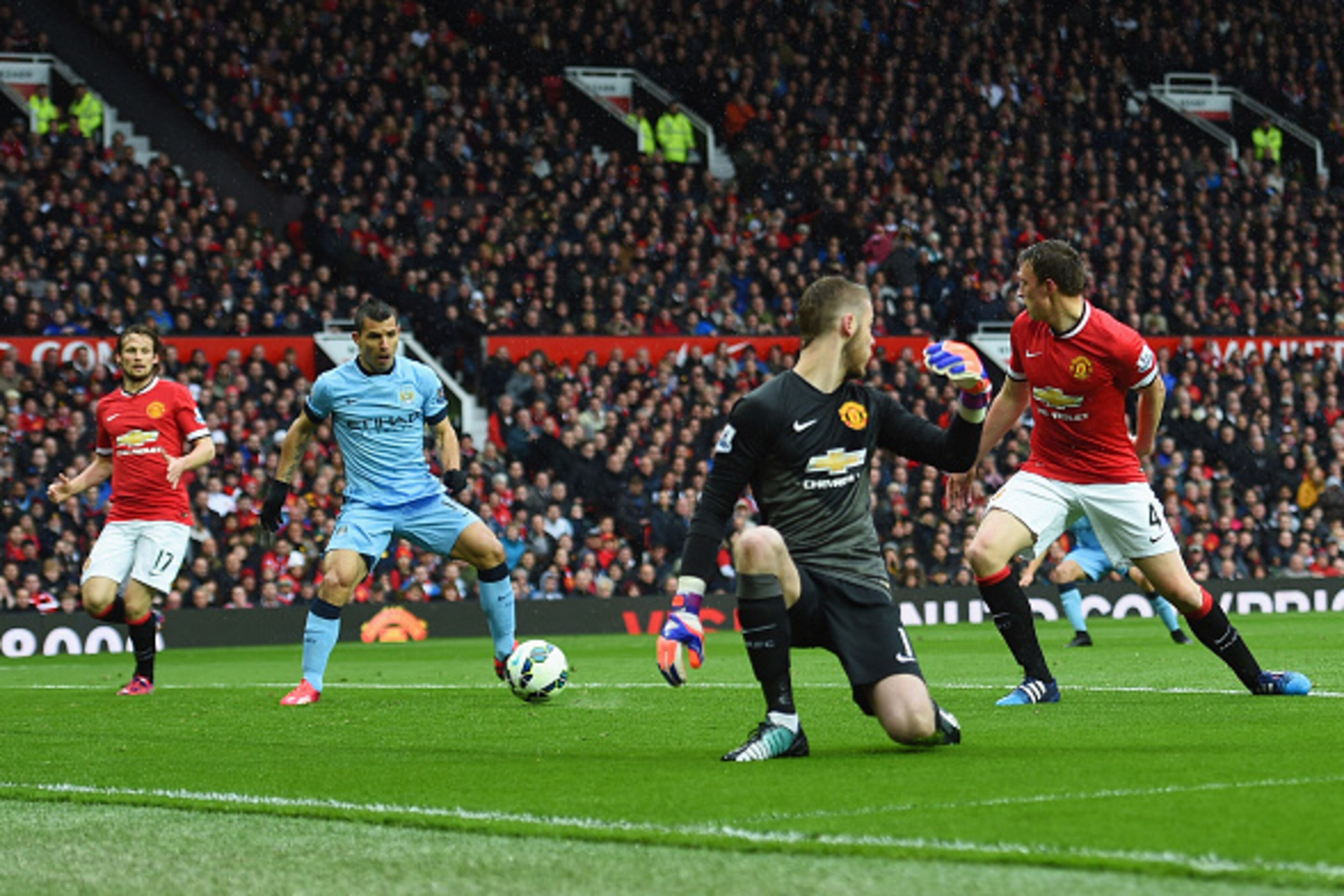 MANCHESTER, ENGLAND - APRIL 12:  Sergio Aguero of Manchester City (2L) scores their first goal as the Manchester United defence look on during the Barclays Premier League match between Manchester United and Manchester City at Old Trafford on April 12, 201