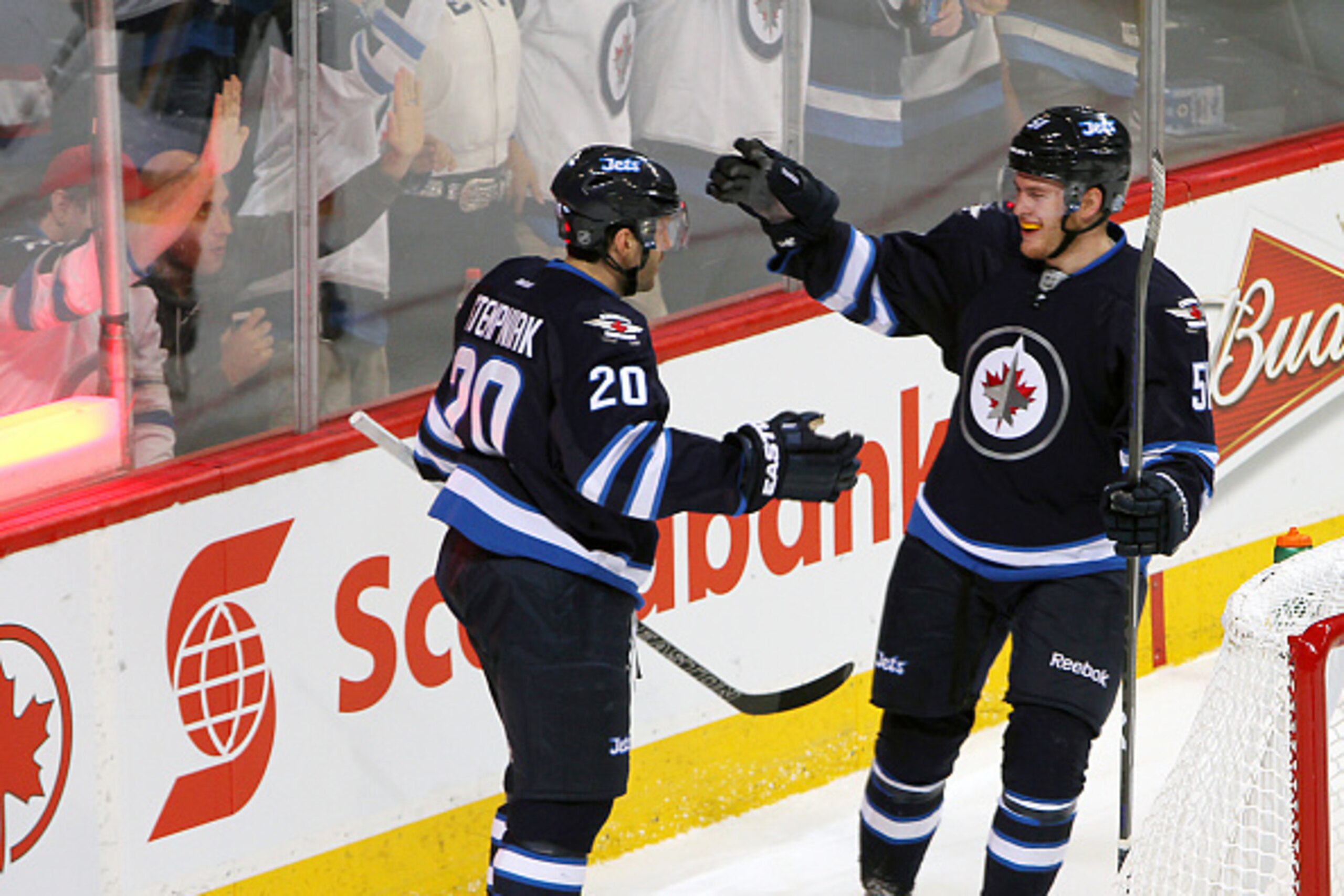 WINNIPEG, CANADA - APRIL 11: Lee Stempniak #20 and Andrew Copp #51 of the Winnipeg Jets celebrate a third period goal against the Calgary Flames on April 11, 2015 at the MTS Centre in Winnipeg, Manitoba, Canada. Copp recorded his first NHL point with an a