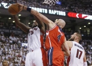Apr 18, 2015; Toronto, Ontario, CAN; Washington Wizards center Marcin Gortat (4) defends against Toronto Raptors forward Amir Johnson (15) as center Jonas Valanciunas (17) looks on in game one of the first round of the NBA Playoffs at Air Canada Centre. W