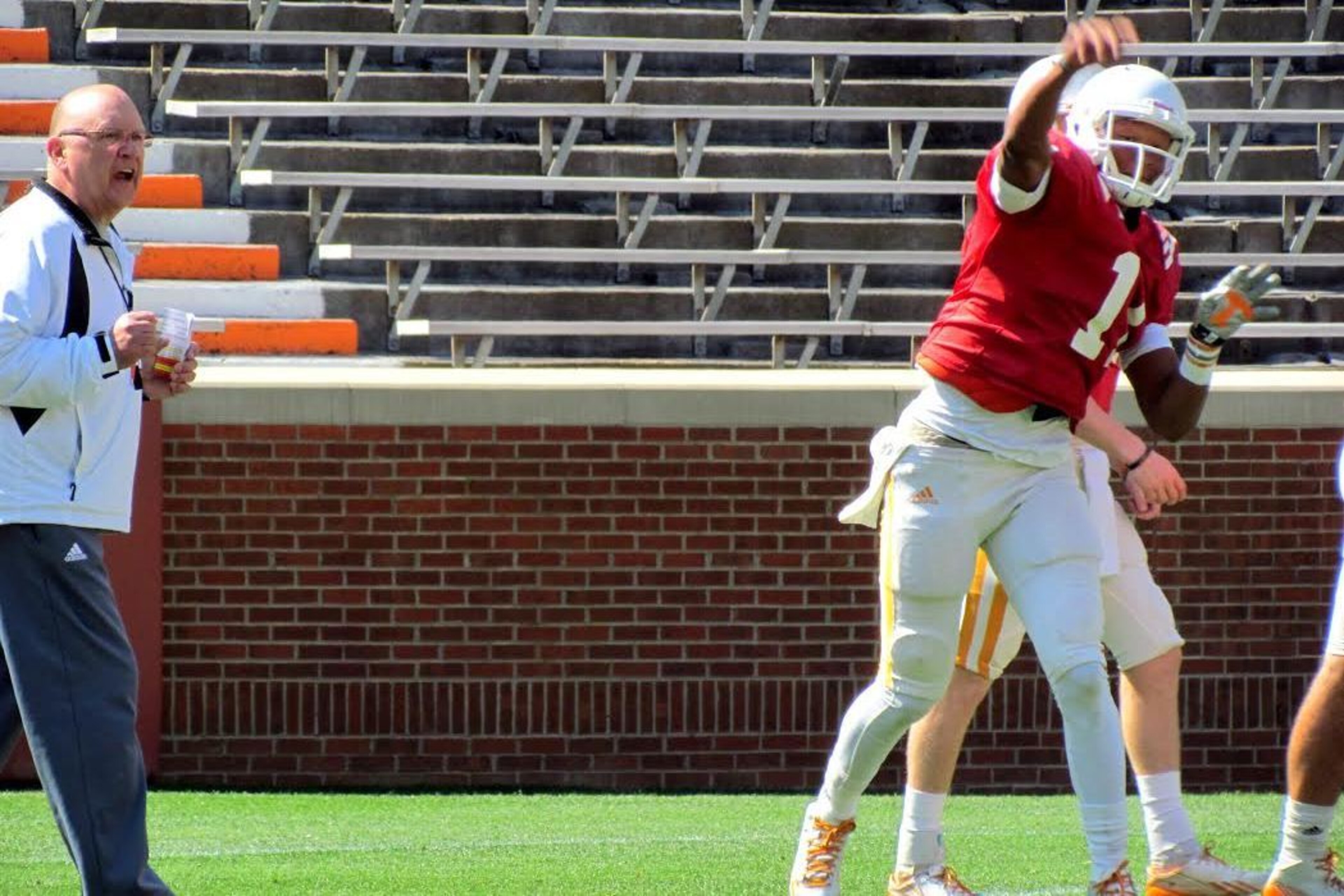 Joshua Dobbs throws a pass as offensive coordinator Mike DeBord looks on.