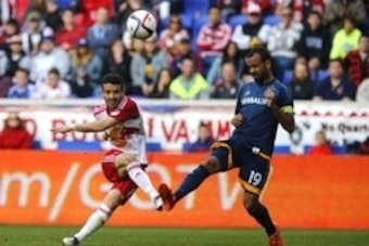 Apr 26, 2015; Harrison, NJ, USA; Los Angeles Galaxy midfielder Juninho (19) defends against a shot by New York Red Bulls forward Peguy Luyindula (8) during second half at Red Bull Arena. Final score 1-1.  Mandatory Credit: Noah K. Murray-USA TODAY Sports