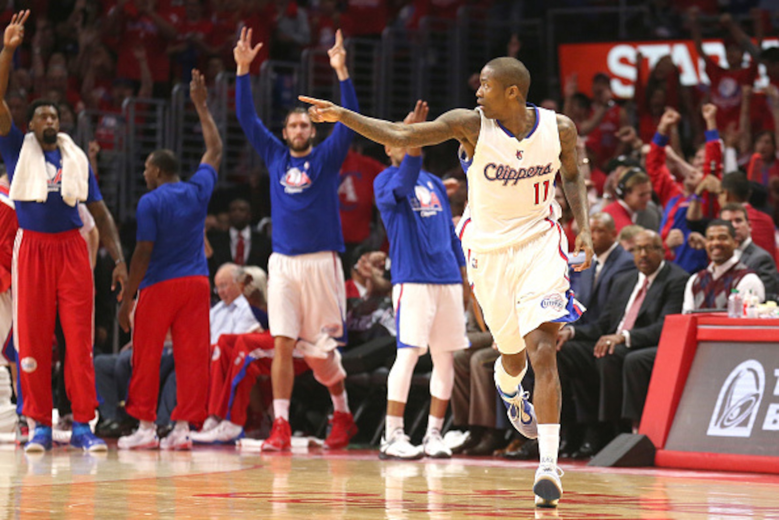 LOS ANGELES, CA - APRIL 19: Jamal Crawford #11 of the Los Angeles Clippers points after making a three point basket as teammates celebrate on the bench against the San Antonio Spurs during Game One of the Western Conference quarterfinals of the 2015 NBA P