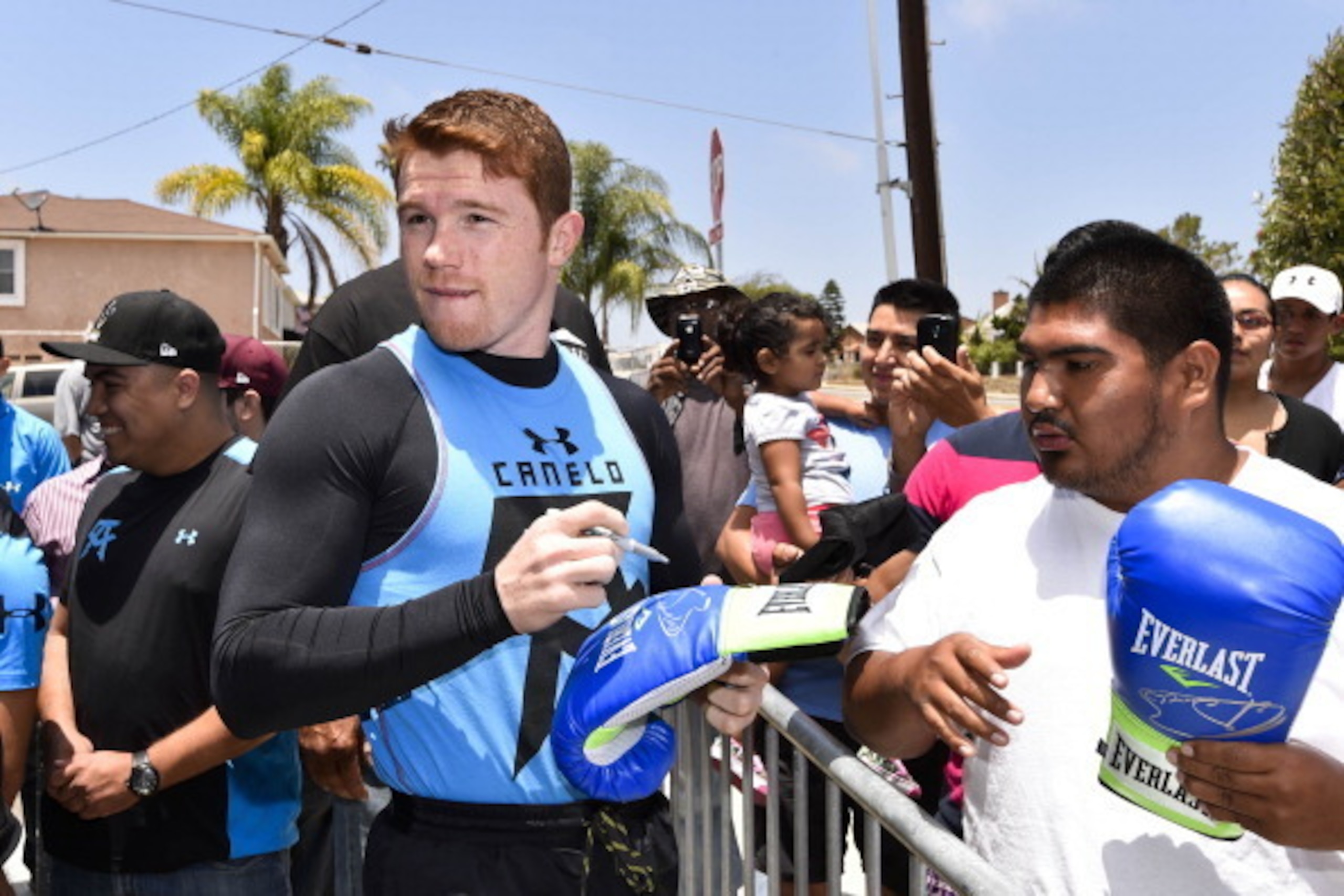 SAN DIEGO, CA - JULY 1:  Canelo Alvarez, former WBC & WBA Super Welterweight World Champion, left, signs an autograph for a fan before training at an open workout at the House of Boxing Gym July 1, 2014 in San Diego, California.  (Photo by Denis Poroy/Get