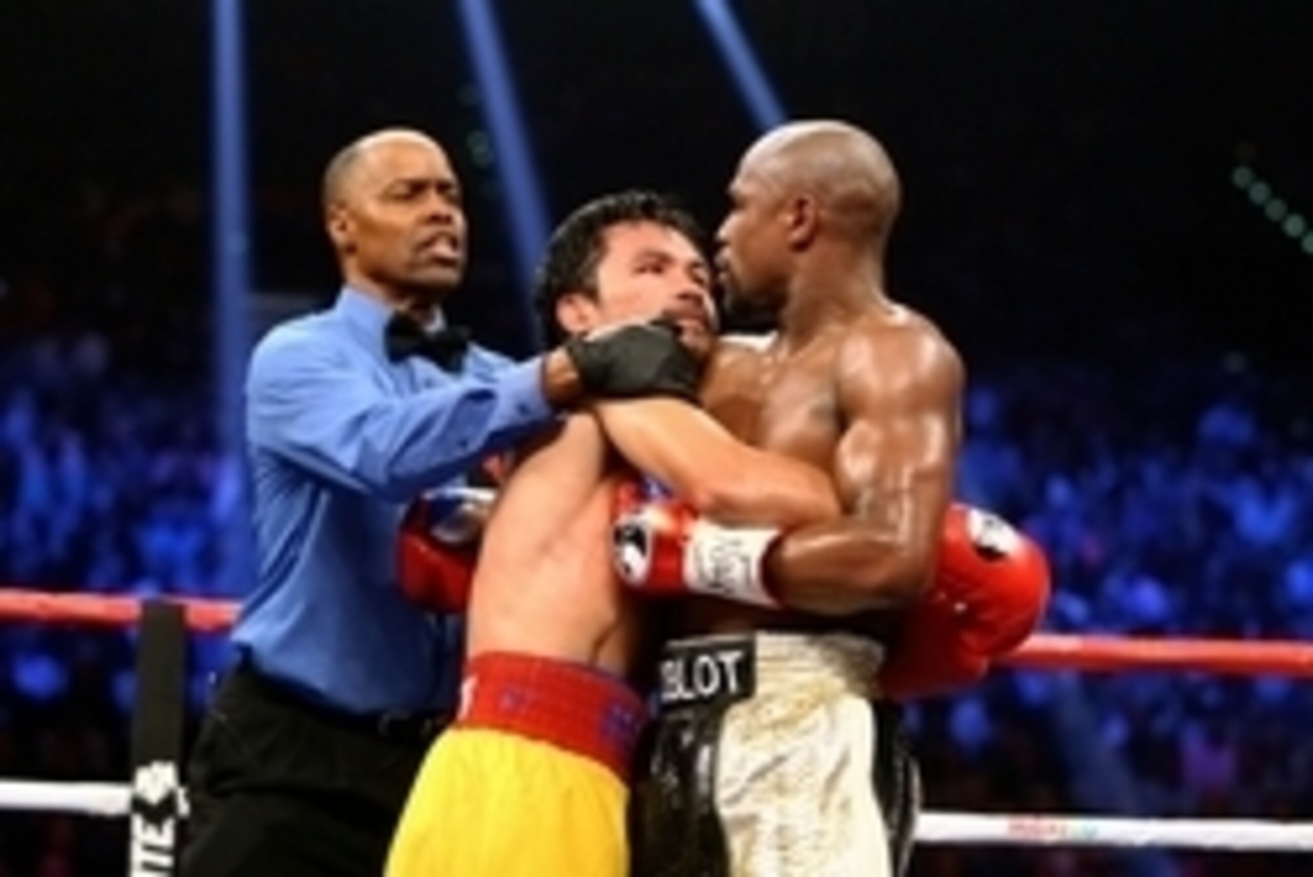 May 2, 2015; Las Vegas, NV, USA; Referee Kenny Bayless (left) attempts to separate Manny Pacquiao (center) as he stares at Floyd Mayweather while being wrapped up during their boxing bout at the MGM Grand Garden Arena. Mandatory Credit: Mark J. Rebilas-US