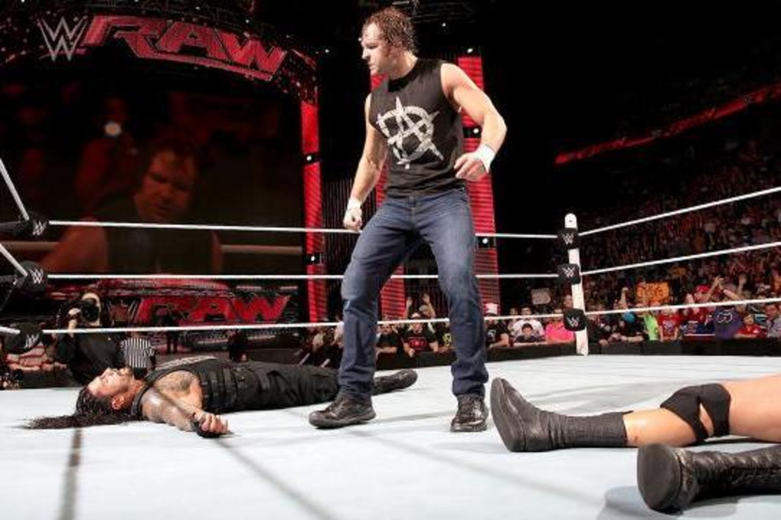 Dean Ambrose stands over Roman Reigns and Randy Orton.