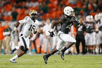 MIAMI GARDENS, FL - NOVEMBER 29: Phillip Dorsett #4 of the Miami Hurricanes is pursued by Reggie Mitchell #15 of the Pittsburgh Panthers as he runs 51 yards for a touchdown after catching a pass from Brad Kaaya #15 (not pictured) during second quarter act