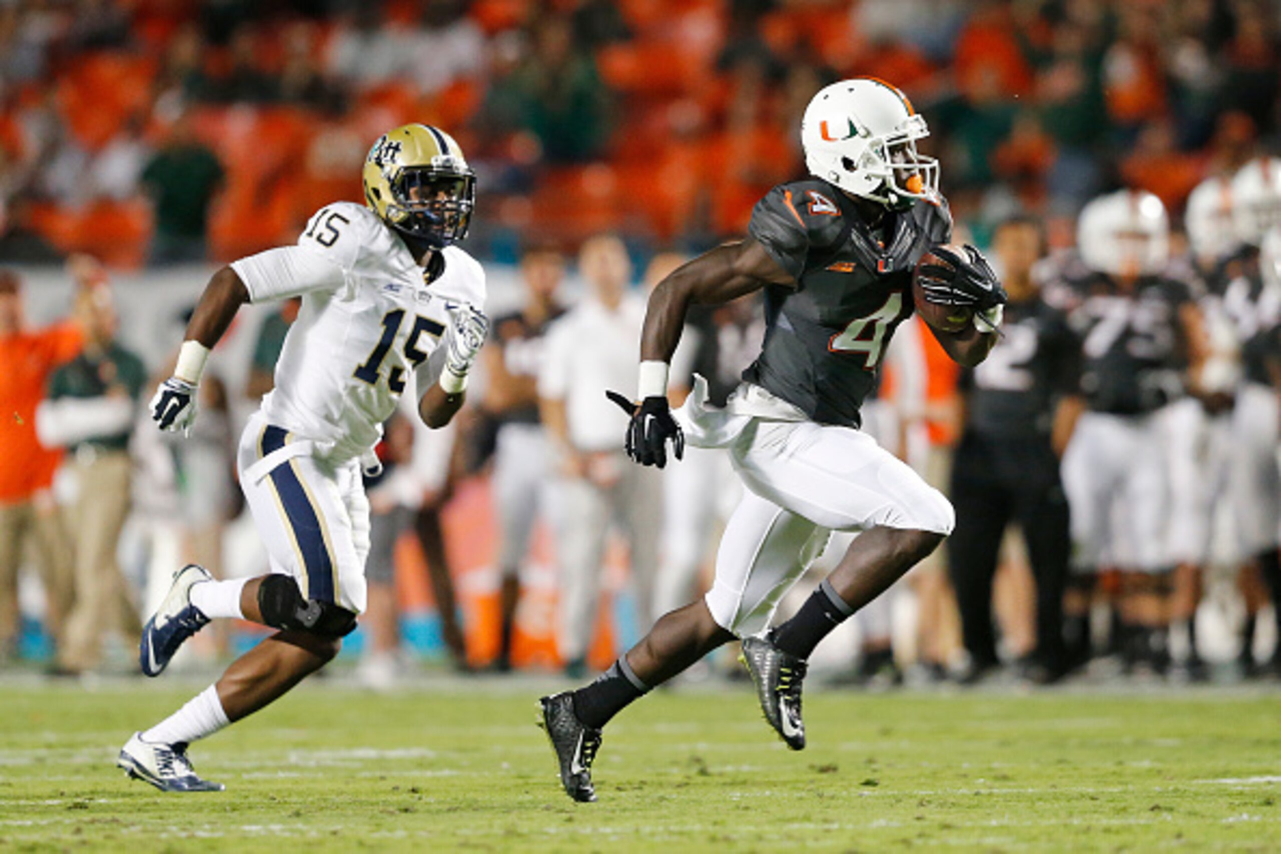 MIAMI GARDENS, FL - NOVEMBER 29: Phillip Dorsett #4 of the Miami Hurricanes is pursued by Reggie Mitchell #15 of the Pittsburgh Panthers as he runs 51 yards for a touchdown after catching a pass from Brad Kaaya #15 (not pictured) during second quarter act