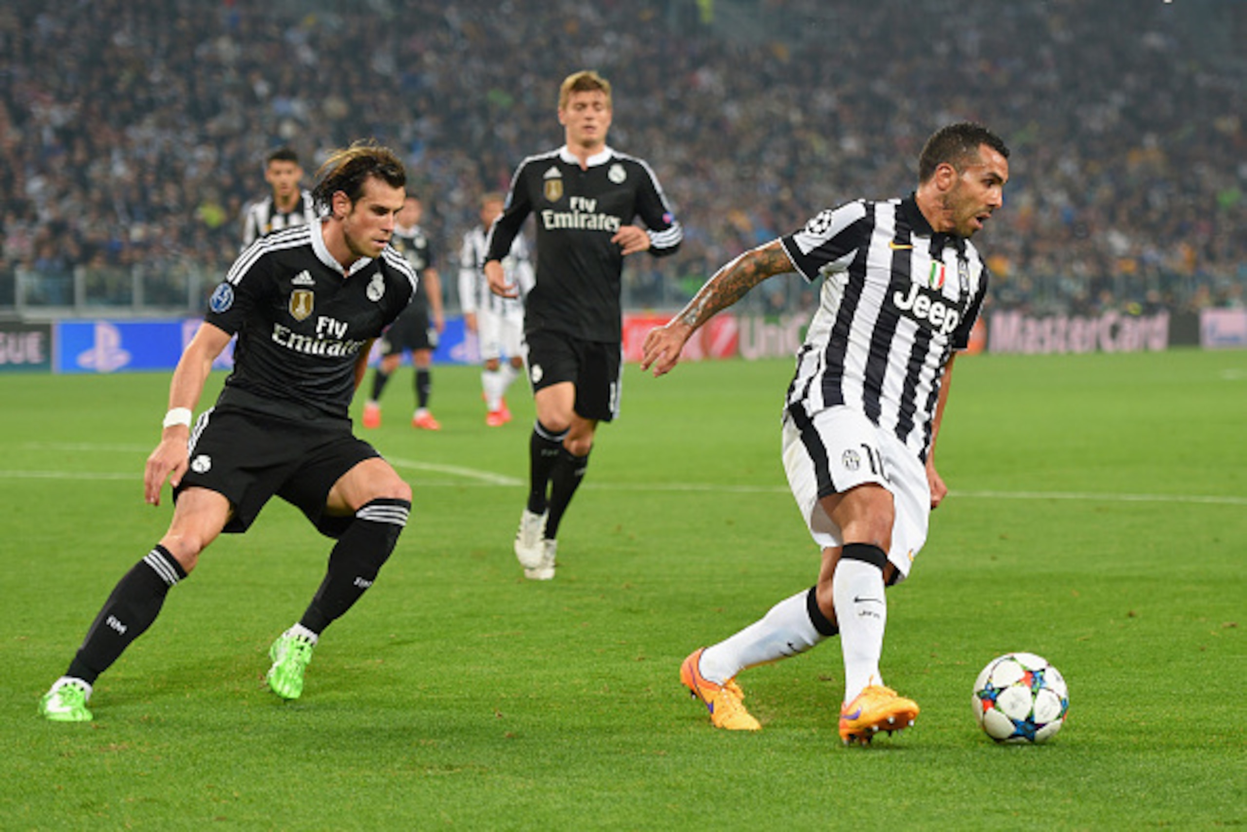 TURIN, ENGLAND - MAY 05:  Carlos Tevez of Juventus is watched by Gareth Bale of Real Madrid CF during the UEFA Champions League semi final first leg match between Juventus and Real Madrid CF at Juventus Arena on May 5, 2015 in Turin, Italy.  (Photo by Mic