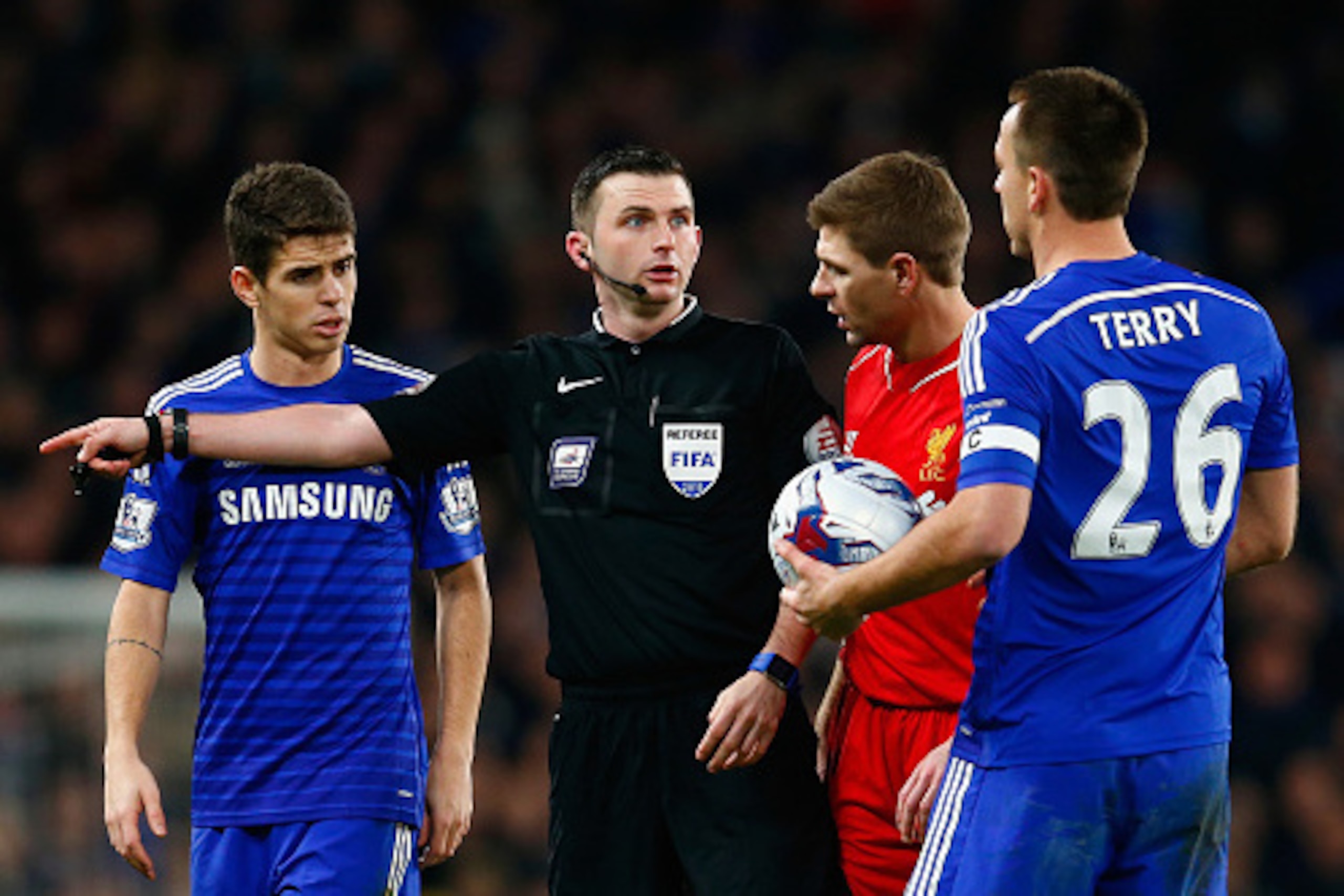 LONDON, ENGLAND - JANUARY 27:  Oscar (L) Steven Gerrard of Liverpool and John Terry of Chelsea speak with Referee Michael Oliver during the Capital One Cup Semi-Final second leg between Chelsea and Liverpool at Stamford Bridge on January 27, 2015 in Londo