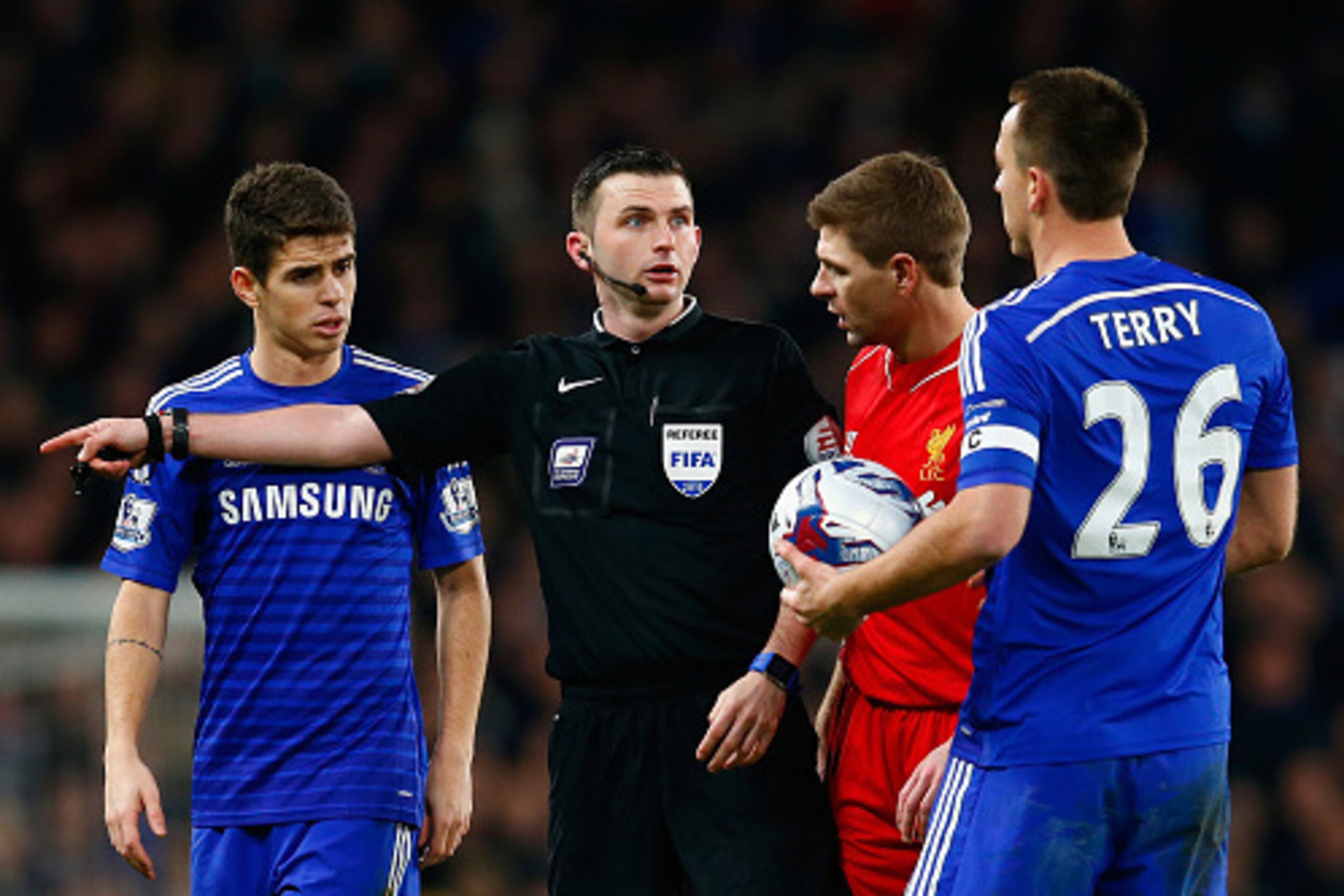 LONDON, ENGLAND - JANUARY 27:  Oscar (L) Steven Gerrard of Liverpool and John Terry of Chelsea speak with Referee Michael Oliver during the Capital One Cup Semi-Final second leg between Chelsea and Liverpool at Stamford Bridge on January 27, 2015 in Londo