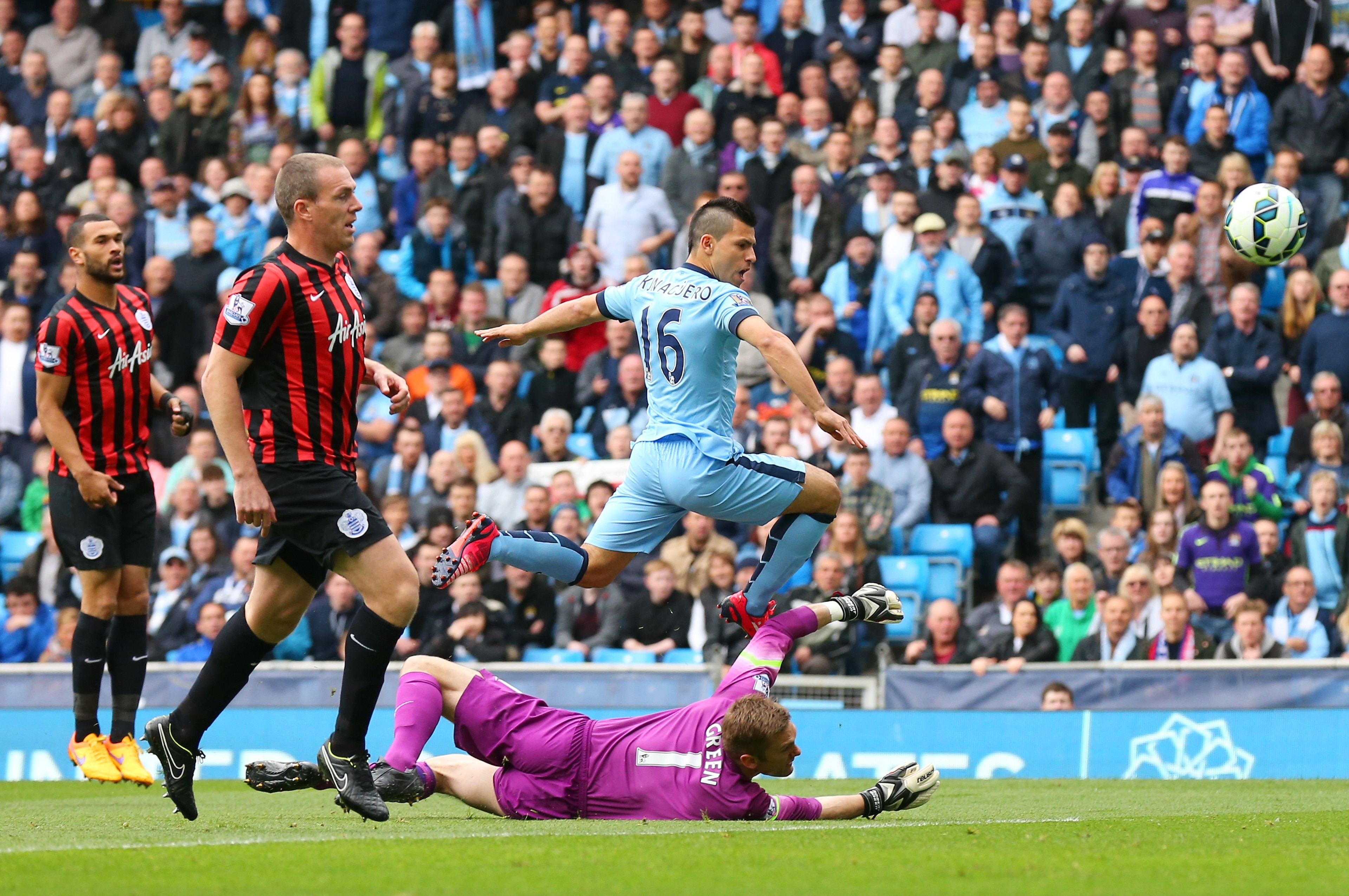 MANCHESTER, ENGLAND - MAY 10:  Sergio Aguero of Manchester City lifts the ball over the diving Robert Green of QPR to score the opening goal during the Barclays Premier League match between Manchester City and Queens Park Rangers at the Etihad Stadium on