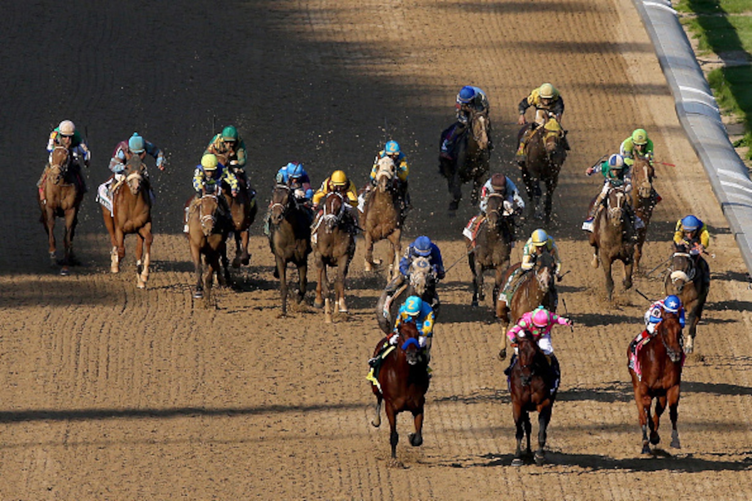 LOUISVILLE, KY - MAY 02:  American Pharoah #18, ridden by Victor Espinoza, Firing Line #10, ridden by Gary Stevens, and Dortmund #8, ridden by Martin Garcia, lead the field as they head for the finish line during the 141st running of the Kentucky Derby at