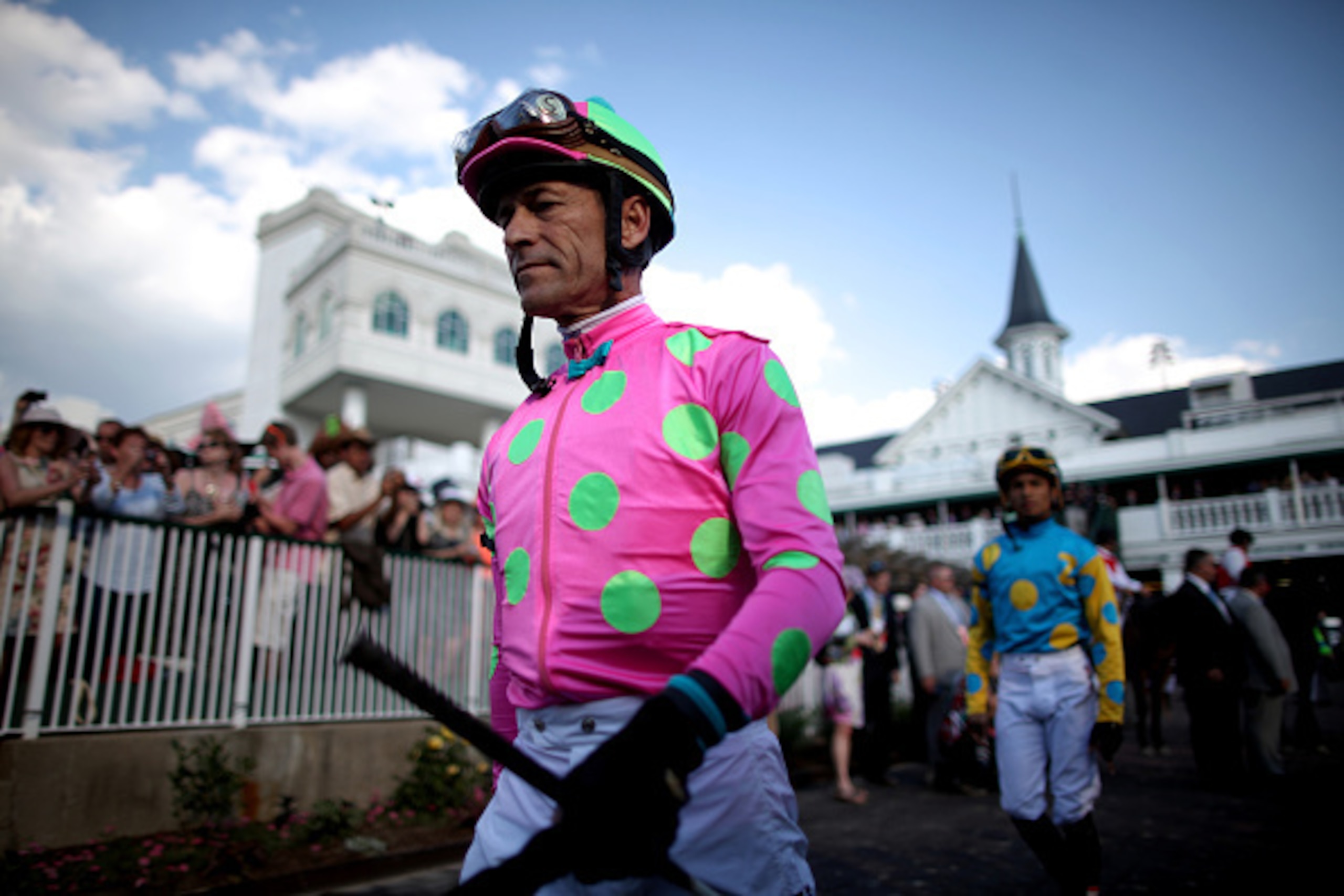 LOUISVILLE, KY - MAY 02:  Jockey Gary Stevens of Firing Line #10 walks ahead of Jockey Victor Espinoza of American Pharoah #18 in the paddock area prior to the 141st running of the Kentucky Derby at Churchill Downs on May 2, 2015 in Louisville, Kentucky. 