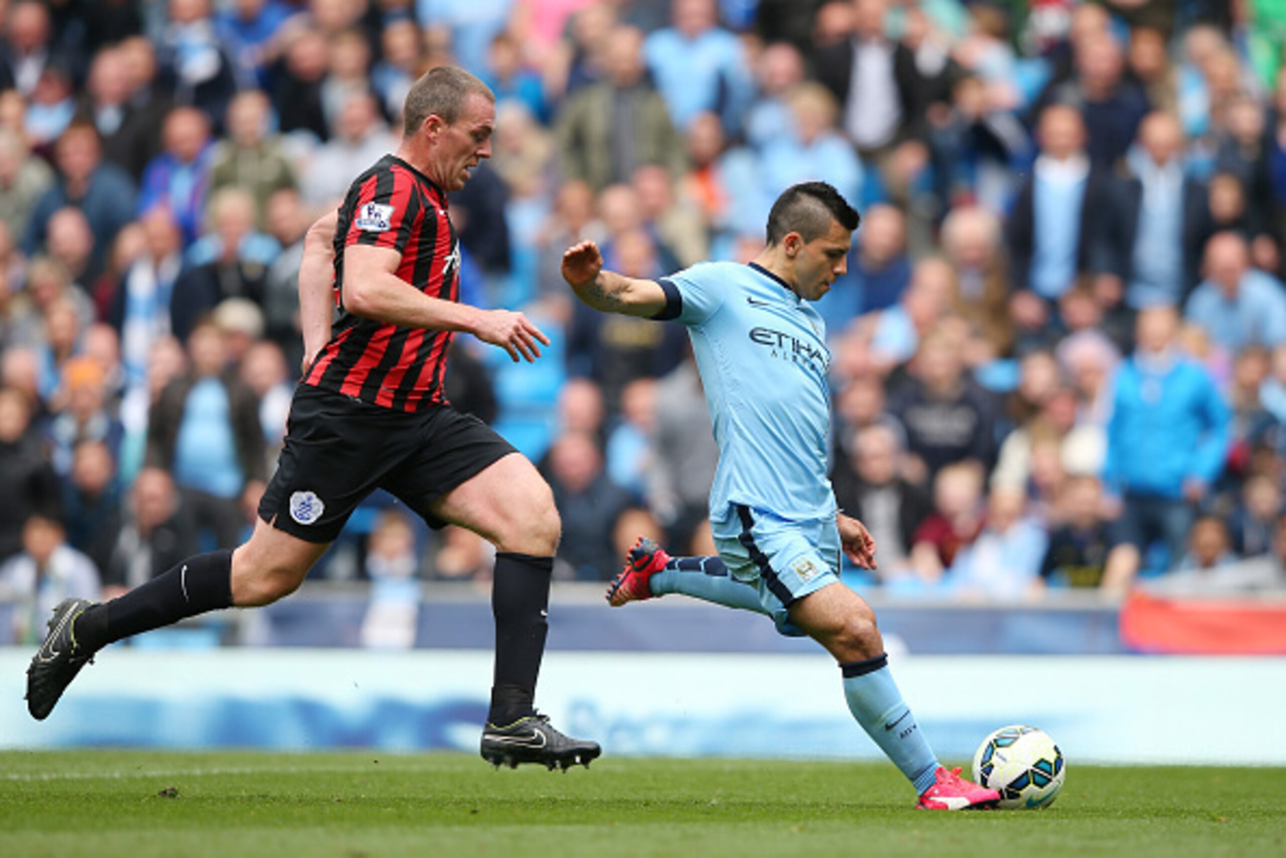 MANCHESTER, ENGLAND - MAY 10:  Sergio Aguero of Manchester City takes a shot on goal as Richard Dunne of QPR closes in during the Barclays Premier League match between Manchester City and Queens Park Rangers at the Etihad Stadium on May 10, 2015 in Manche