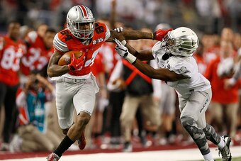 ARLINGTON, TX - JANUARY 12:  Wide receiver Corey Smith #84 of the Ohio State Buckeyes stiff arms Reggie Daniels of the Oregon Ducks before fumbling the ball in the second quarter during the College Football Playoff National Championship Game at AT&T Stadi