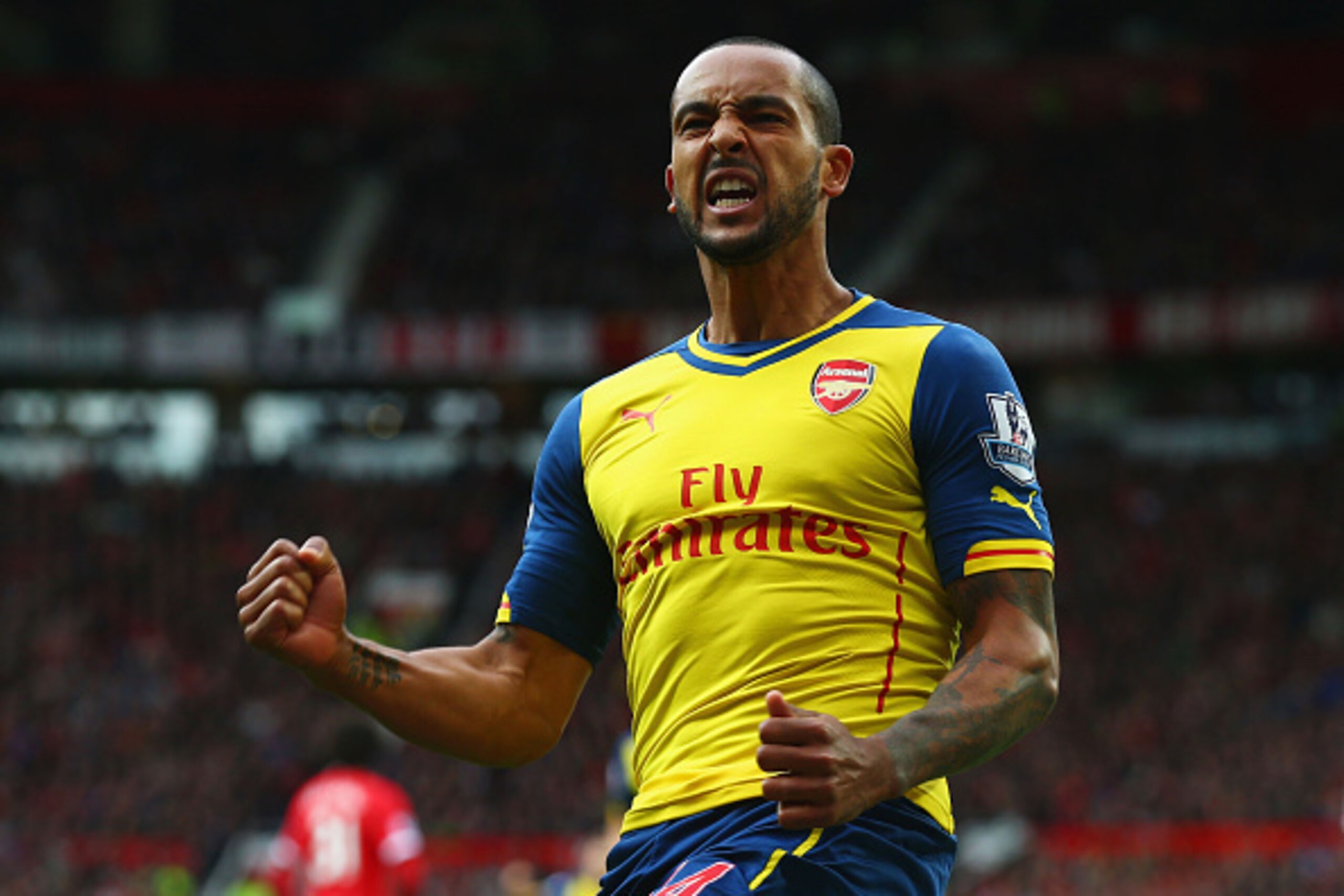 MANCHESTER, ENGLAND - MAY 17: Theo Walcott of Arsenal celebrates as his cross deflects off of Tyler Blackett of Manchester United for an own goal during the Barclays Premier League match between Manchester United and Arsenal at Old Trafford on May 17, 20 MANCHESTER, ENGLAND - MAY 17: Theo Walcott of Arsenal celebrates as his cross deflects off of Tyler Blackett of Manchester United for an own goal during the Barclays Premier League match between Manchester United and Arsenal at Old Trafford on May 17, 20