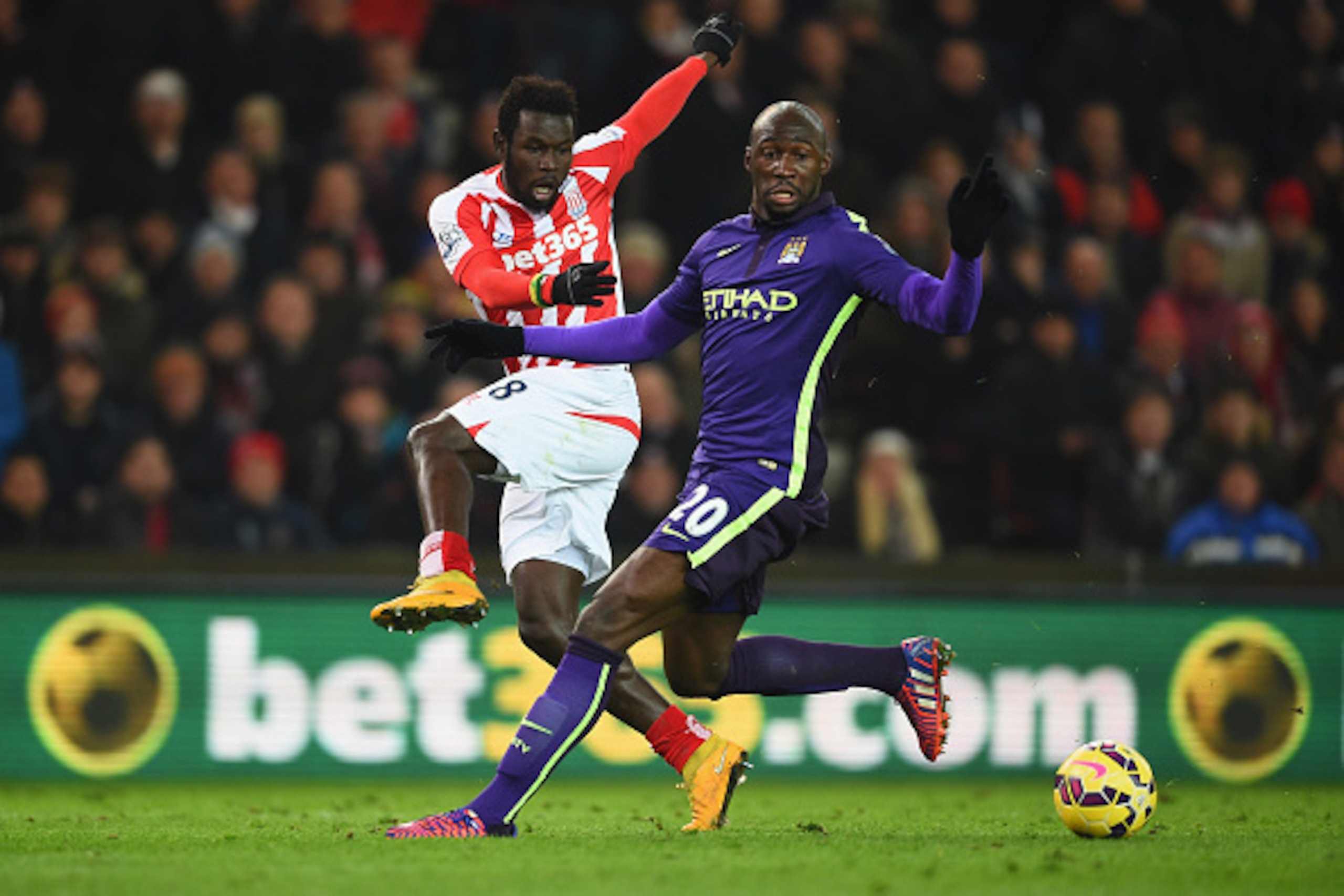 STOKE ON TRENT, ENGLAND - FEBRUARY 11: Mane Diouf of Stoke fires in a shot under pressure from Eliaquim Mangala of Manchester City during the Barclays Premier League match between Stoke City and Manchester City at Britannia Stadium on February 11, 2015 in