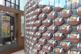 A multi-story wall of glass encases 915 footballs, one for each UM win.