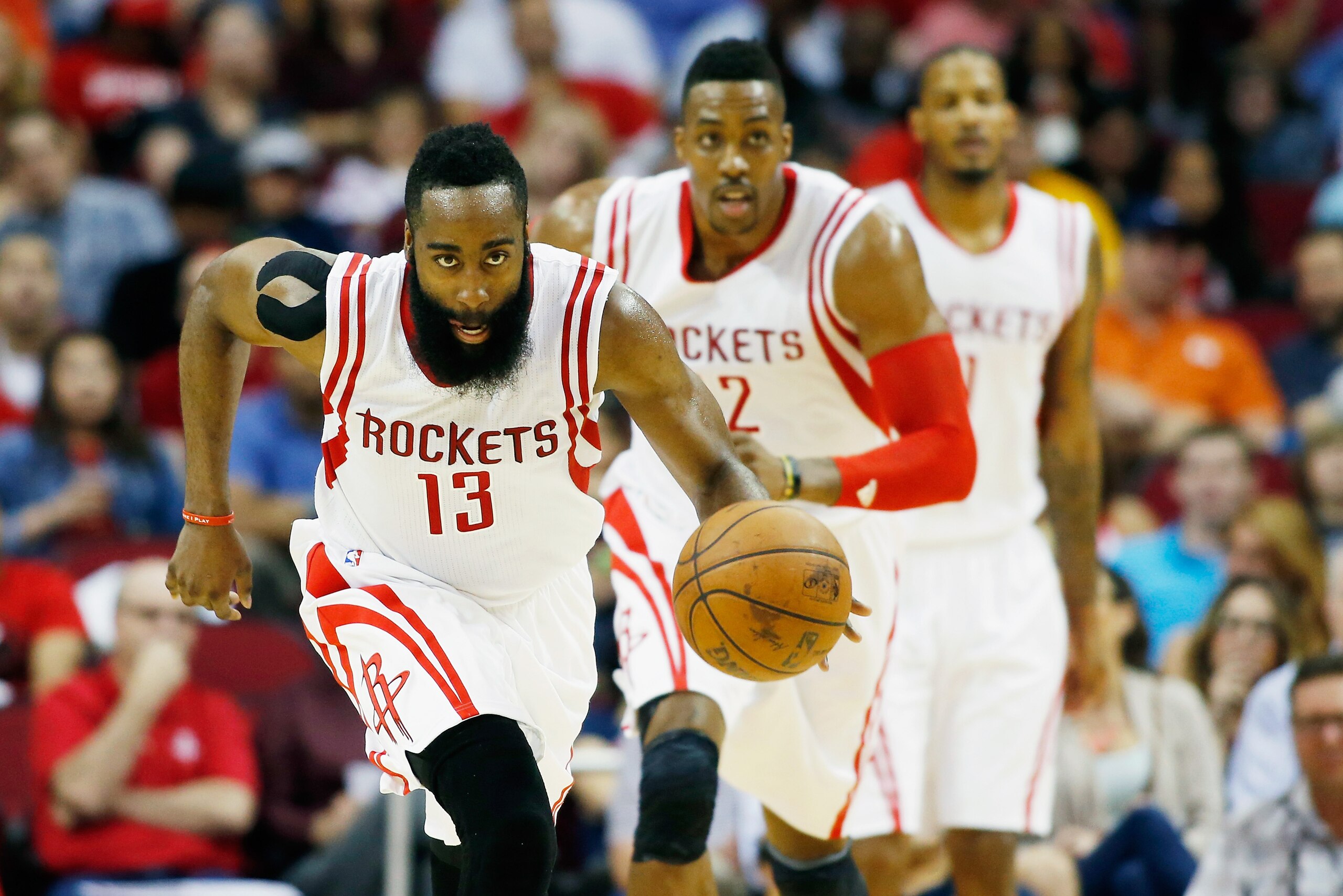 HOUSTON, TX - APRIL 15:   James Harden #13 of the Houston Rockets takes the baskeball upcourt as Dwight Howard #12 and Trevor Ariza #1 look on during their game against the Utah Jazzat the Toyota Center on April 15, 2015 in Houston, Texas. NOTE TO USER: U