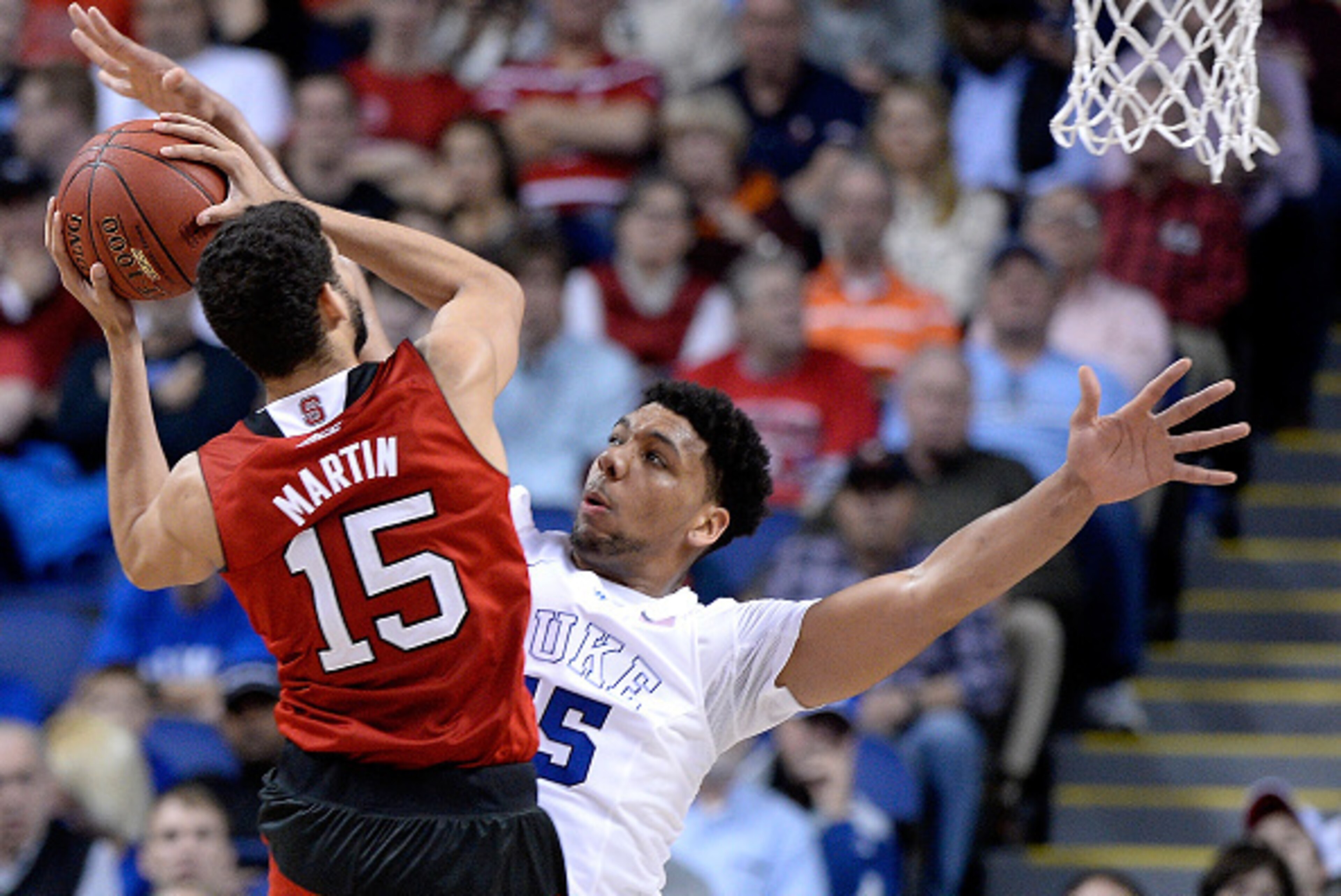 GREENSBORO, NC - MARCH 12:  Jahlil Okafor #15 of the Duke Blue Devils challenges a shot by Cody Martin #15 of the North Carolina State Wolfpack during the quarterfinals of the ACC Basketball Tournament at Greensboro Coliseum on March 12, 2015 in Greensbor